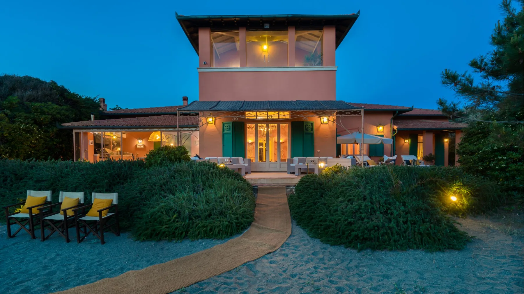 A modern building glows at dusk behind a curved garden path.
