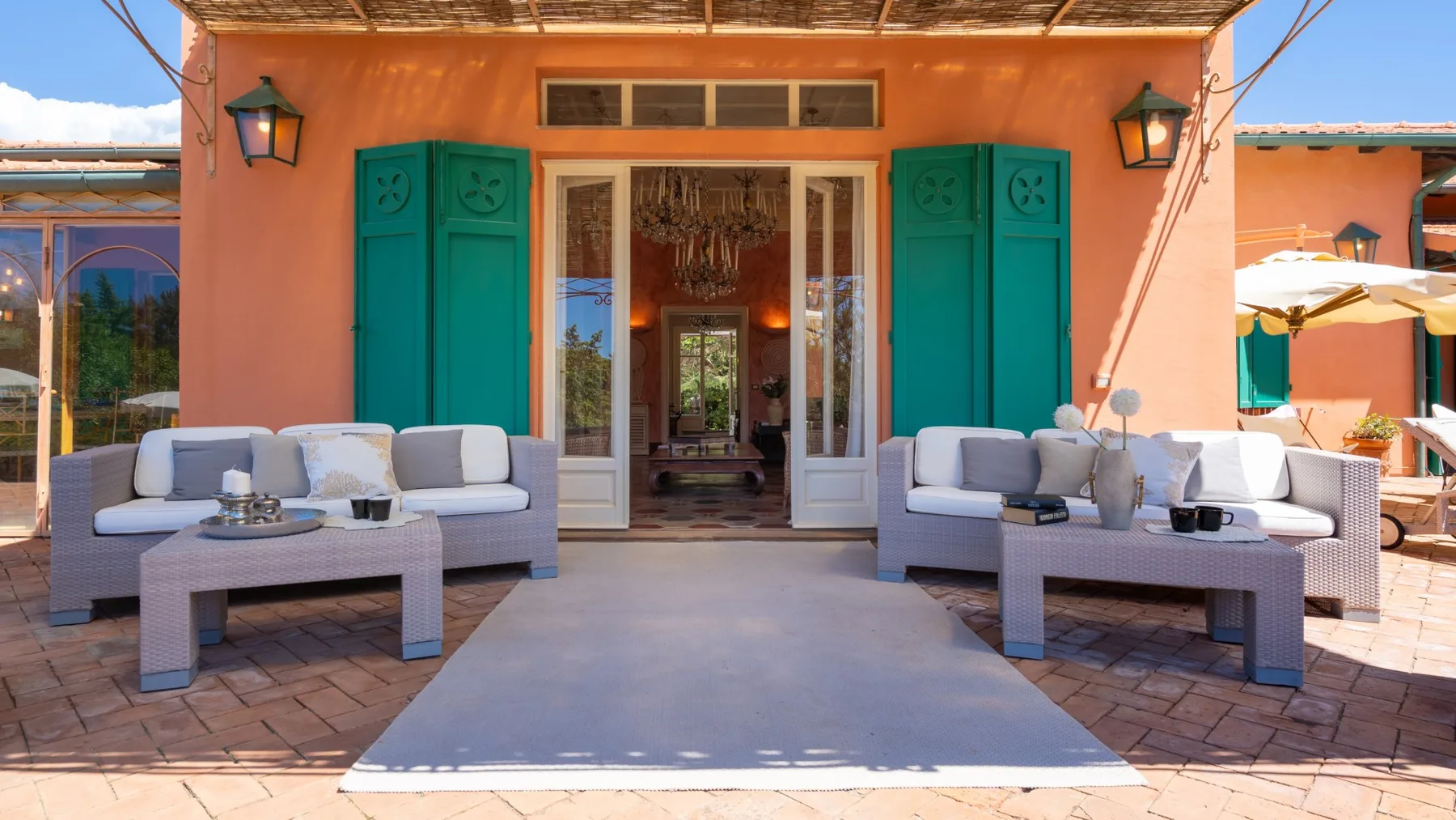 An outdoor seating area faces open doors with teal shutters.