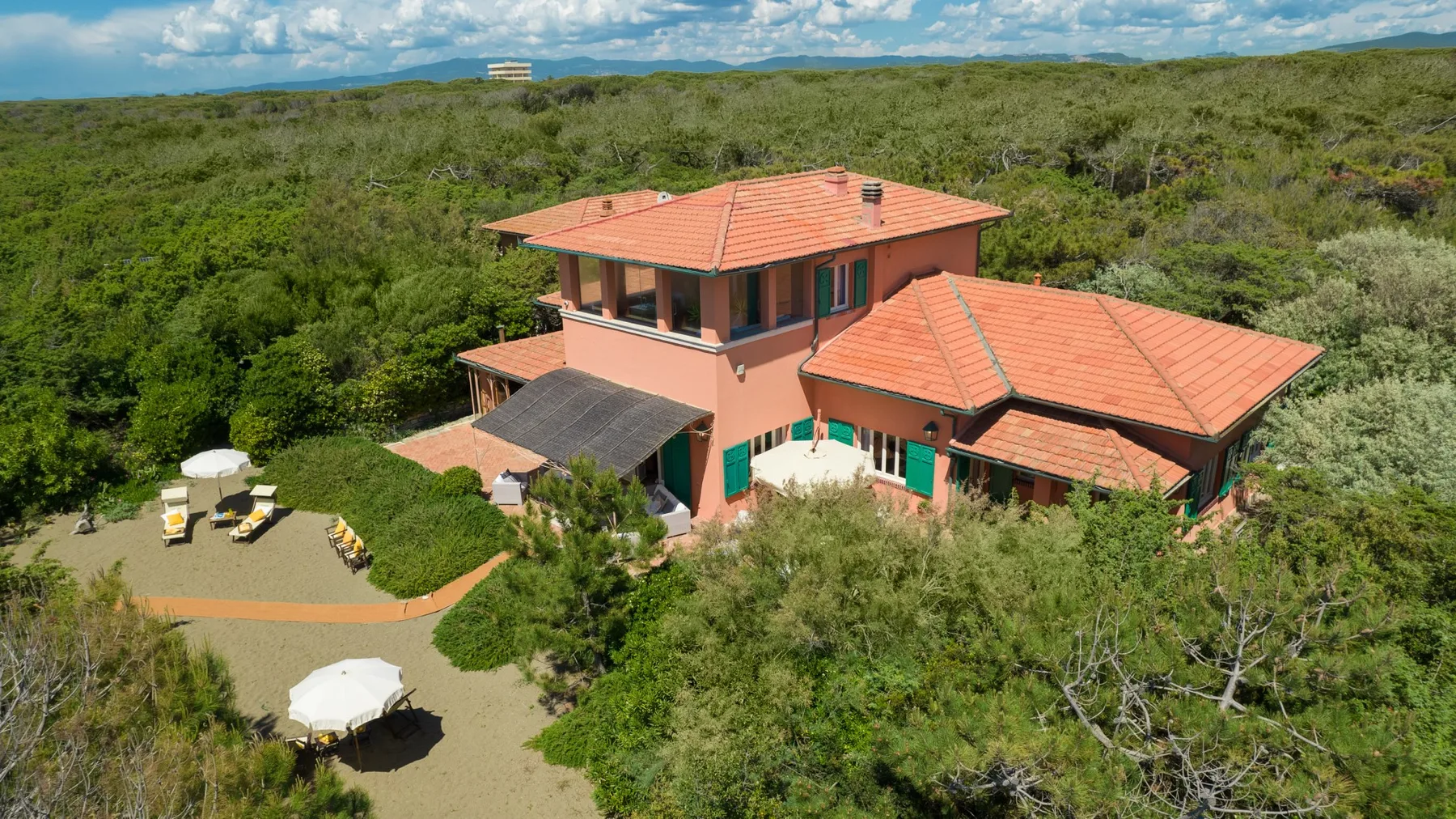A terracotta-roofed house stands amid dense green vegetation.
