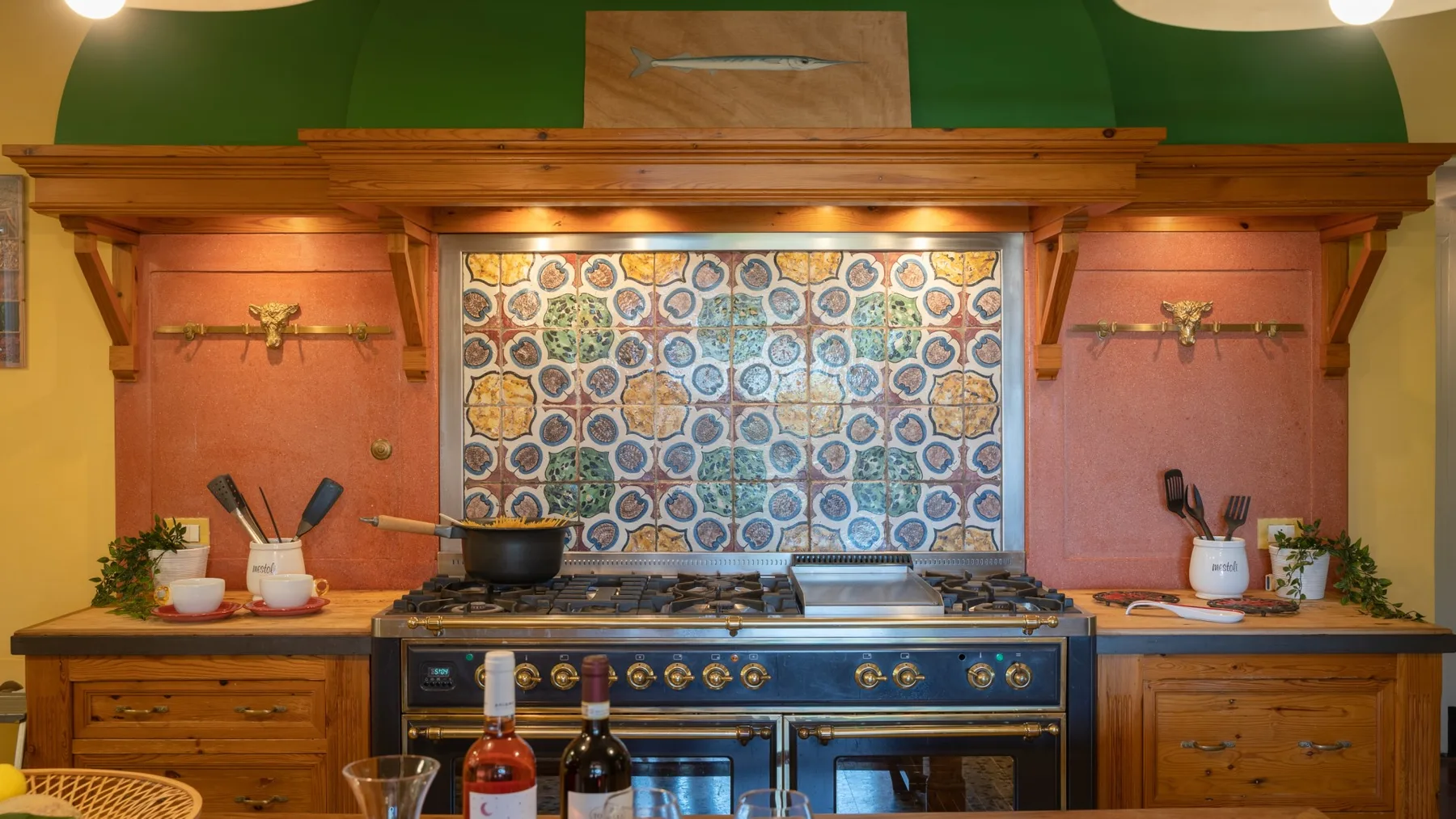 A kitchen cooking range sits beneath a colorful patterned tile backsplash.