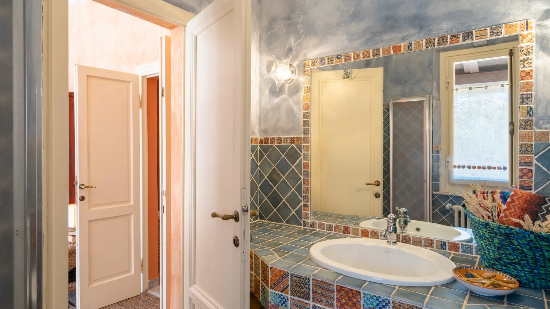 A tiled bathroom with a large sink and a window.