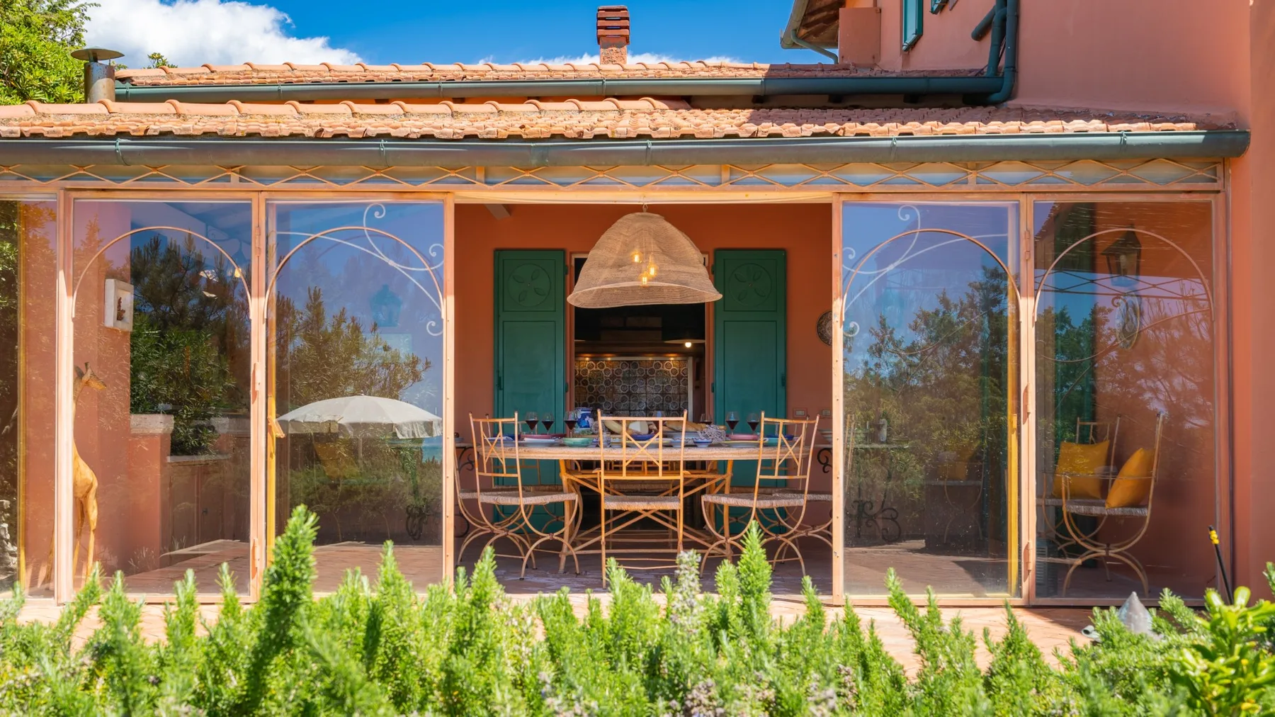 A patio dining area sits behind glass doors, with a table and chairs under a hanging light.