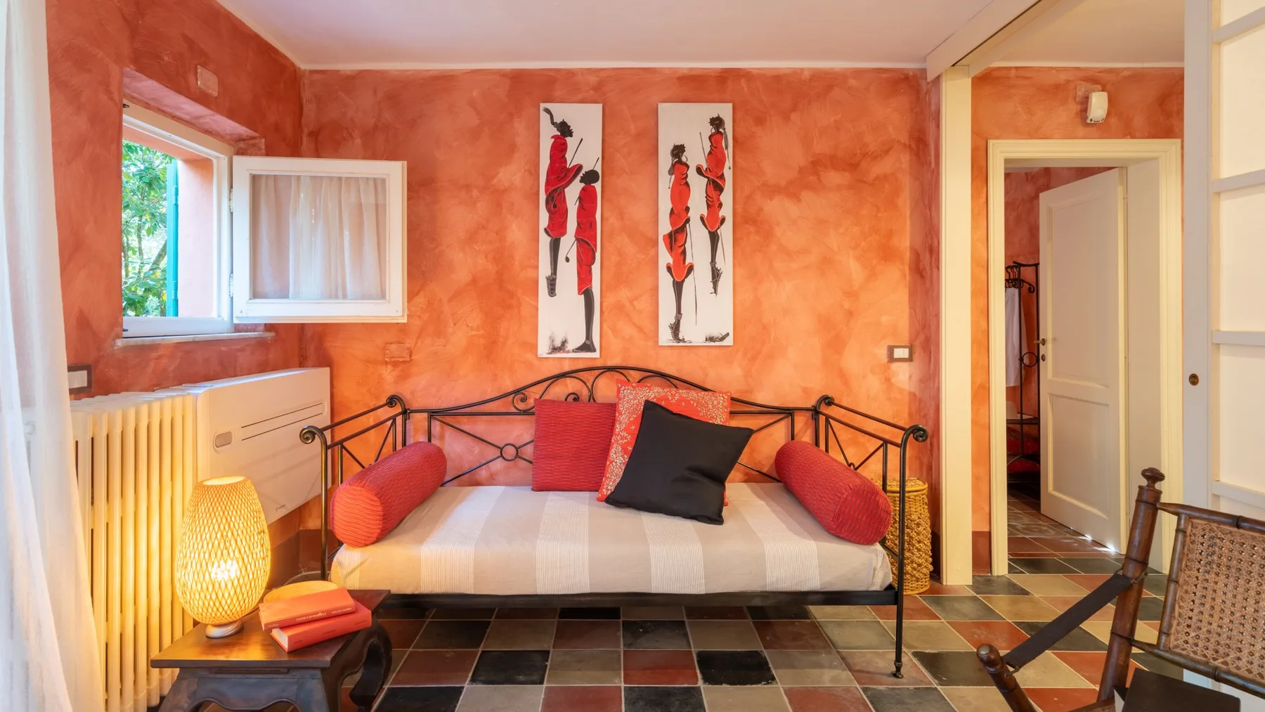 A bedroom with a daybed, colorful walls, and framed artwork.
