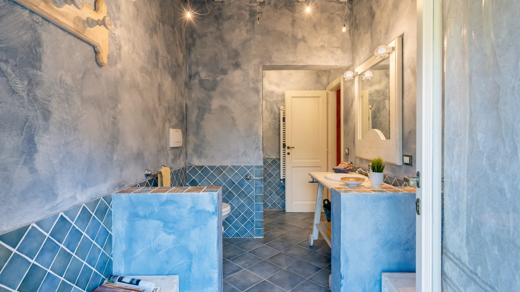 A bathroom with a blue-tiled counter and a large mirror.