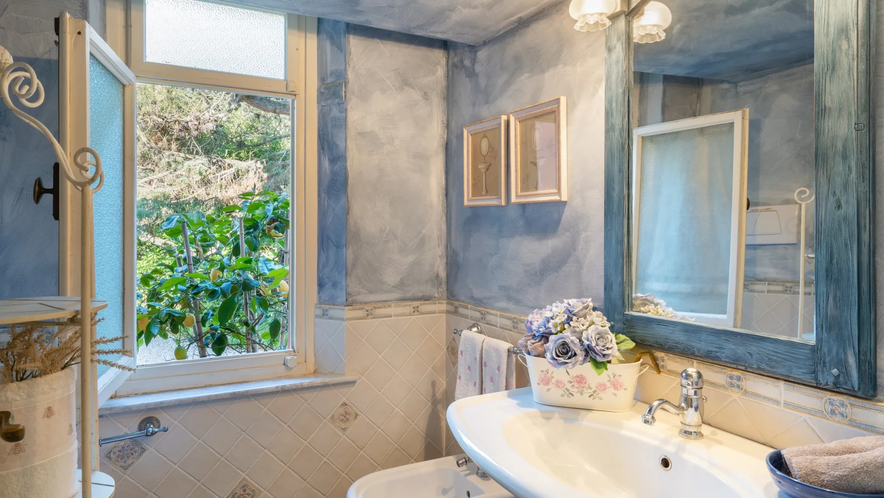 A bathroom with a white sink and a window overlooking greenery.