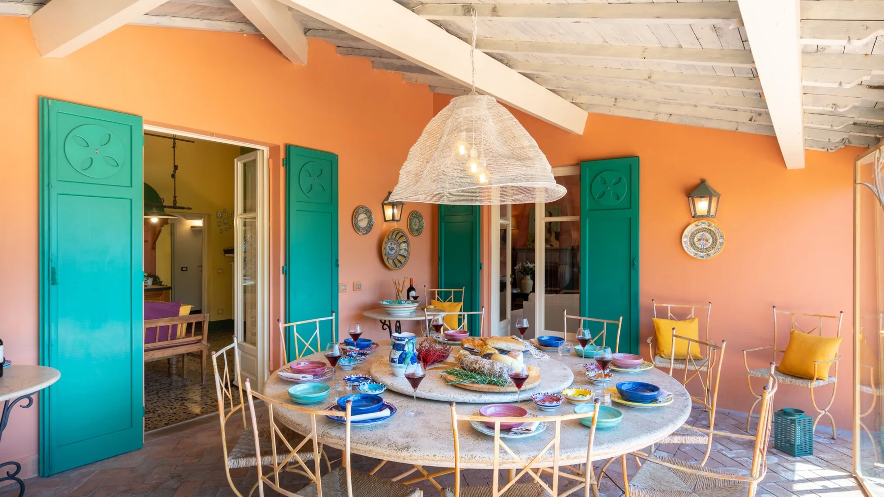 An outdoor dining area with a large table set beneath a woven pendant light.
