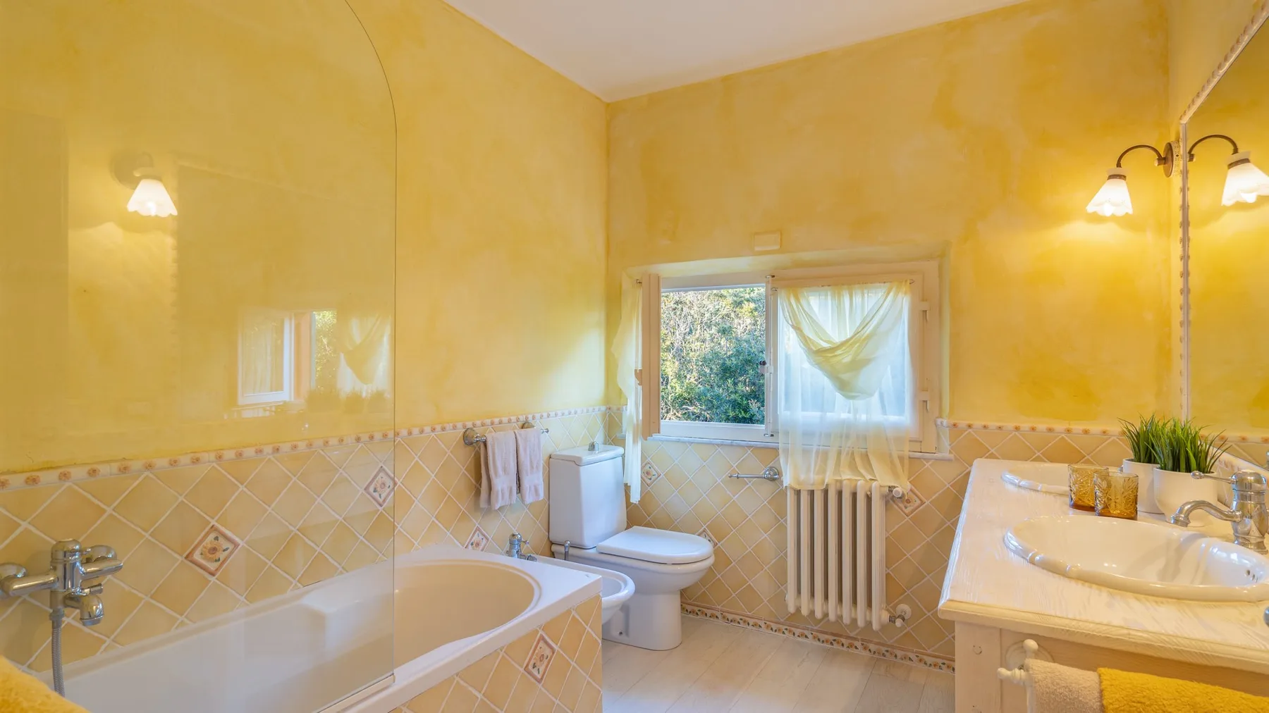 A yellow bathroom with a bathtub, toilet, and sink.