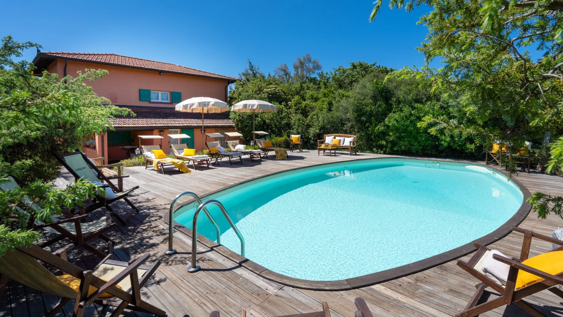 An outdoor swimming pool is surrounded by a wooden deck and lounge seating.