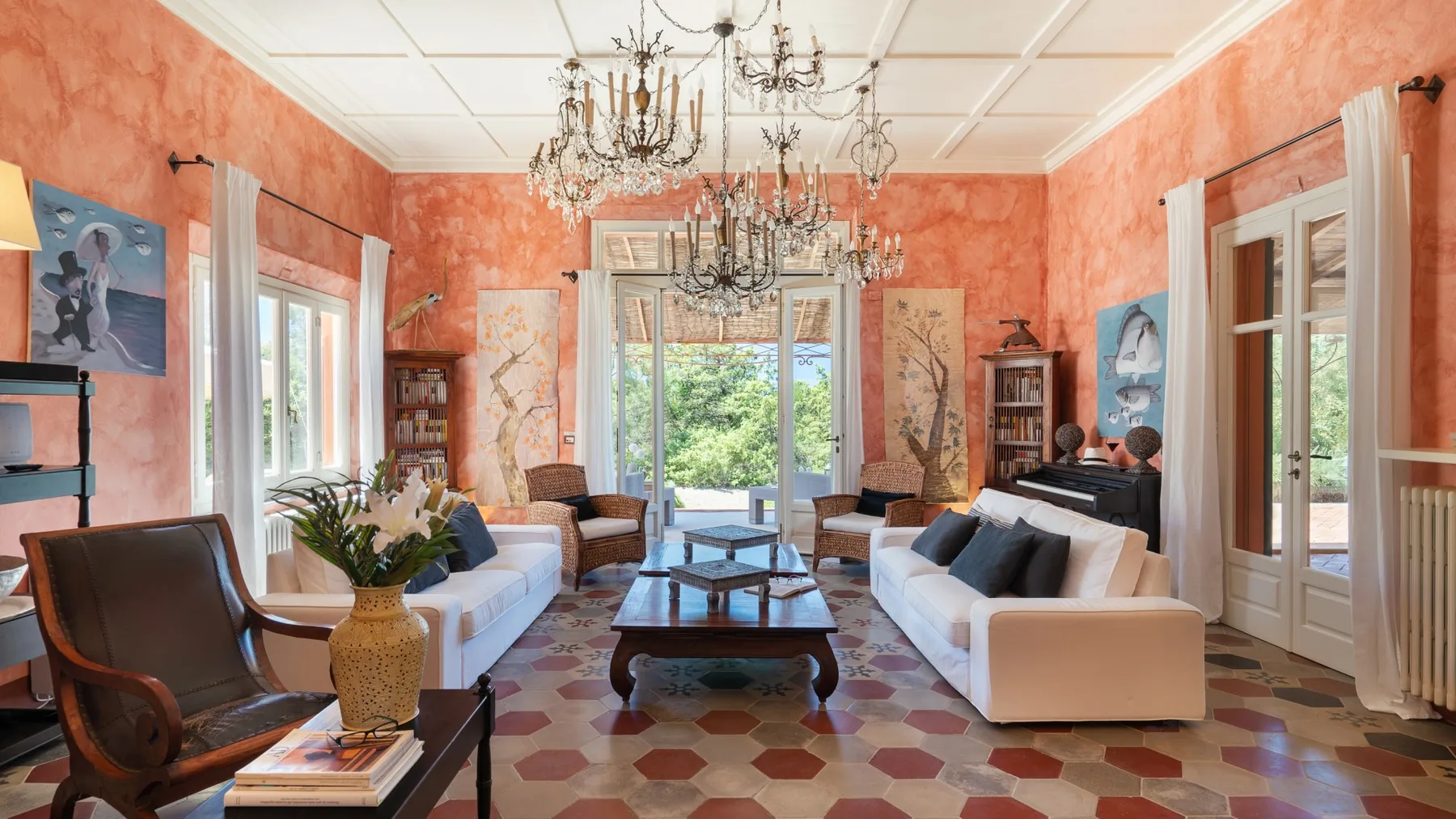 A living room with seating arranged around a central coffee table and several chandeliers.