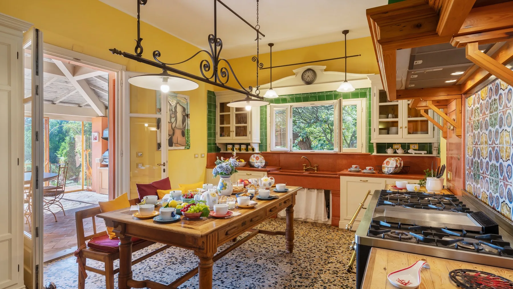 A bright kitchen with a wooden dining table set with dishes and food.