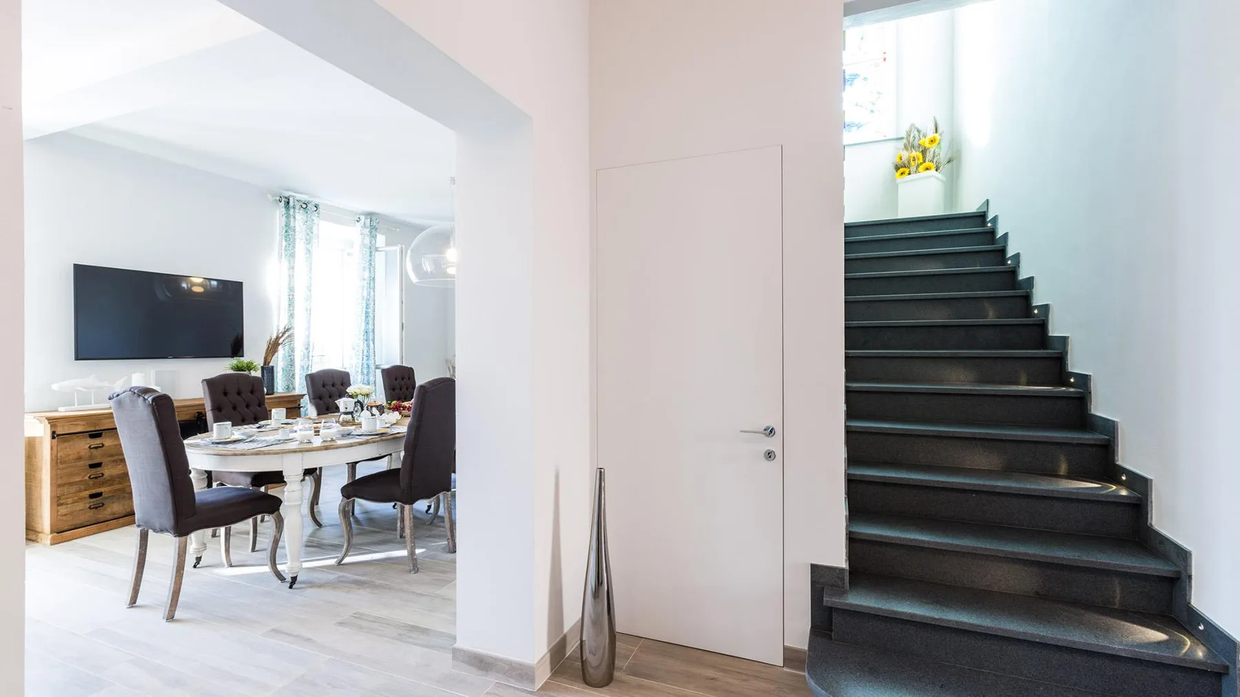 A dining area beside a staircase, with a table and chairs.