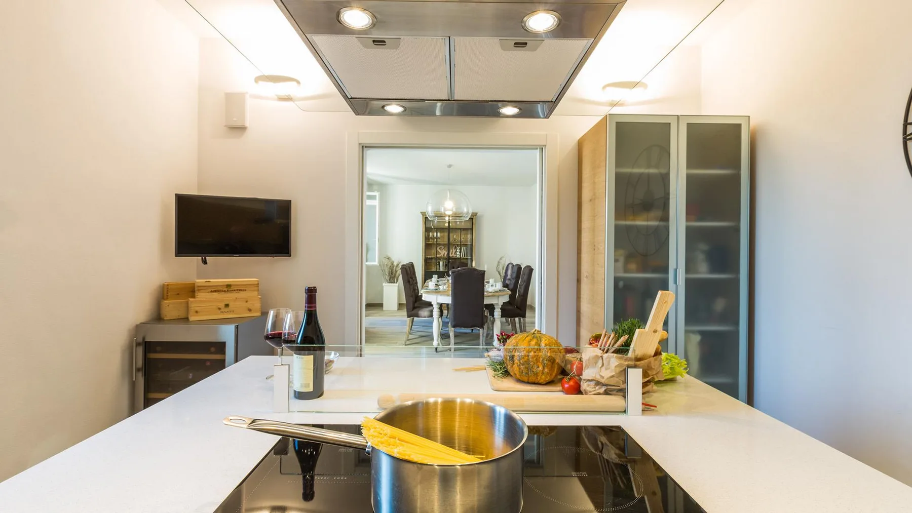 A bright kitchen with a pot on the cooktop and a dining area beyond.