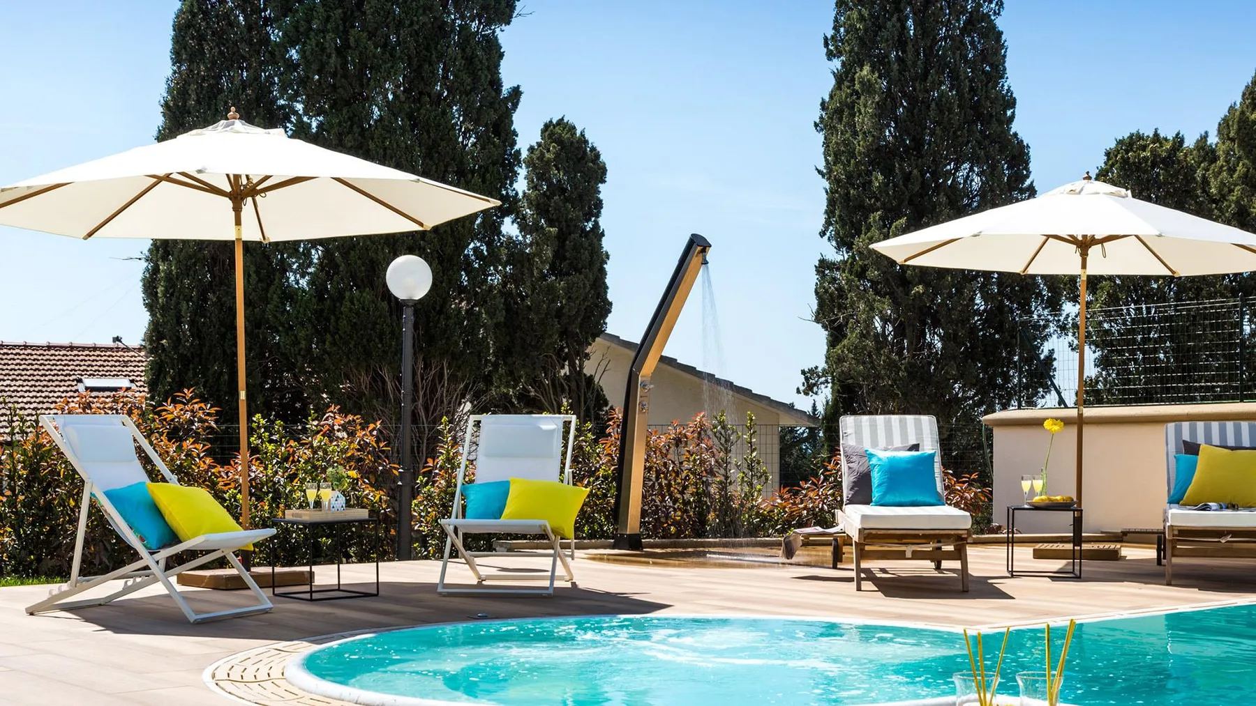 An outdoor swimming pool is surrounded by lounge seating and sun umbrellas.