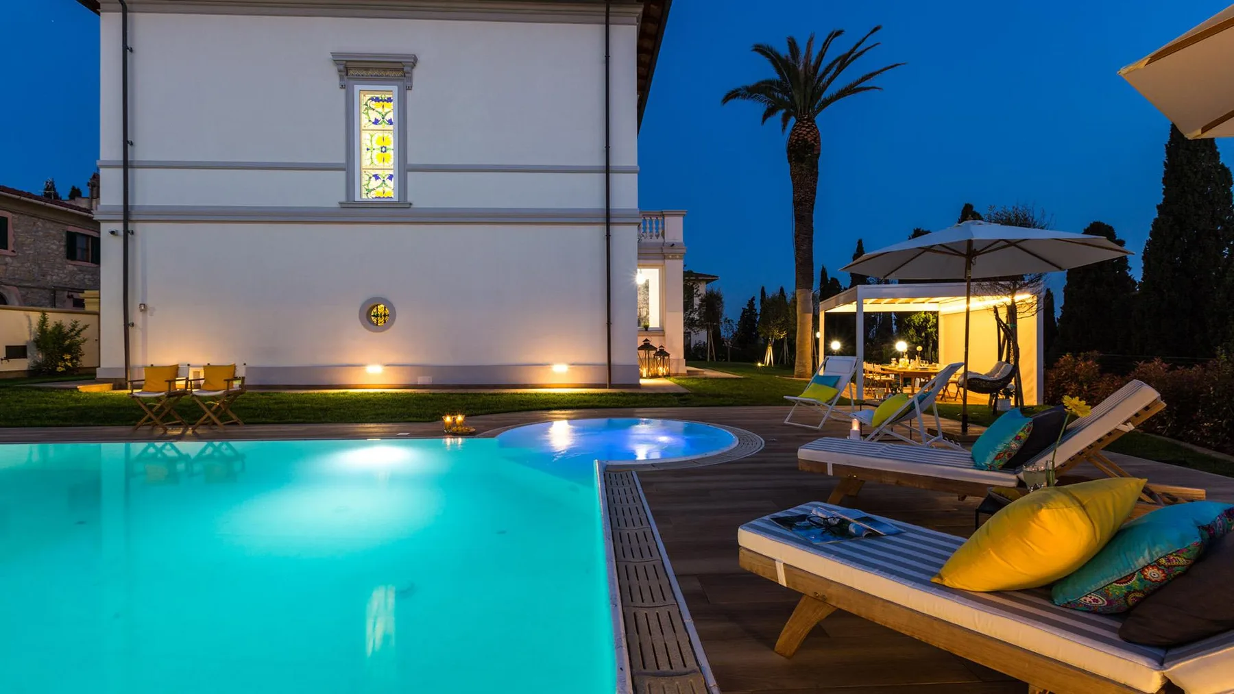 An outdoor swimming pool beside a building, with lounge seating on the deck.
