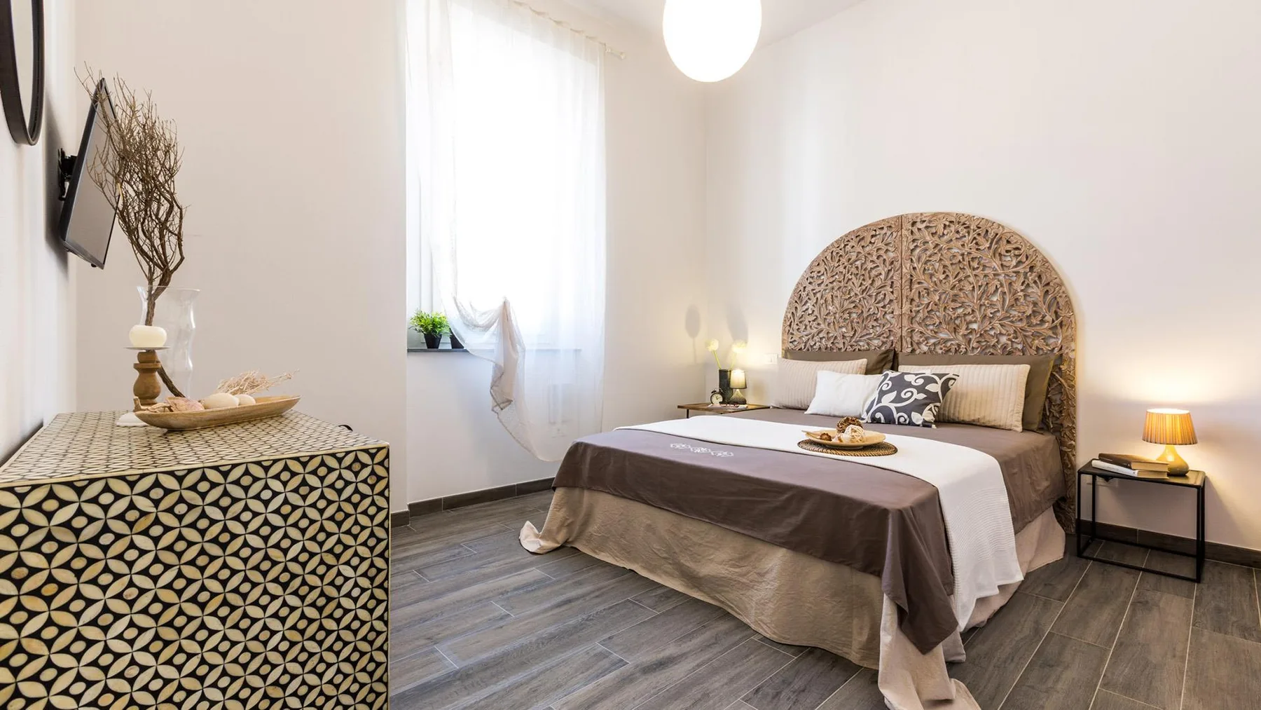 A bedroom with a bed, bedside tables, and a patterned dresser.