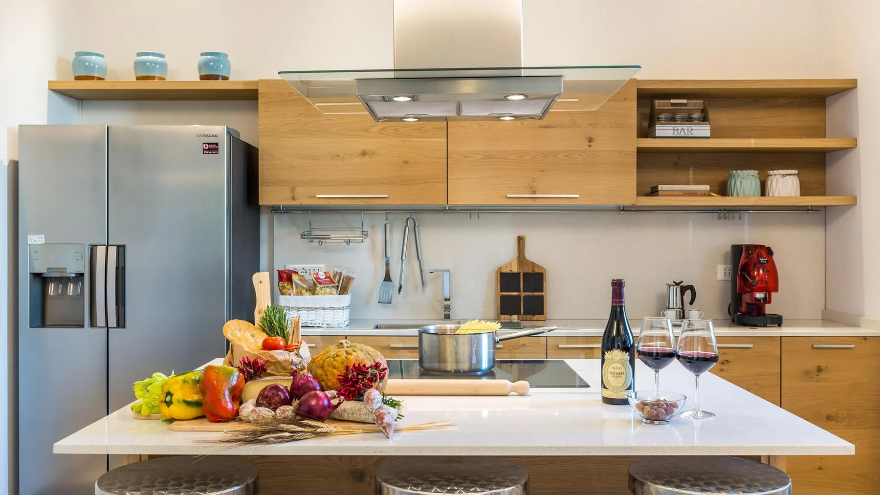 A modern kitchen with wooden cabinets and a large island topped with fresh produce.