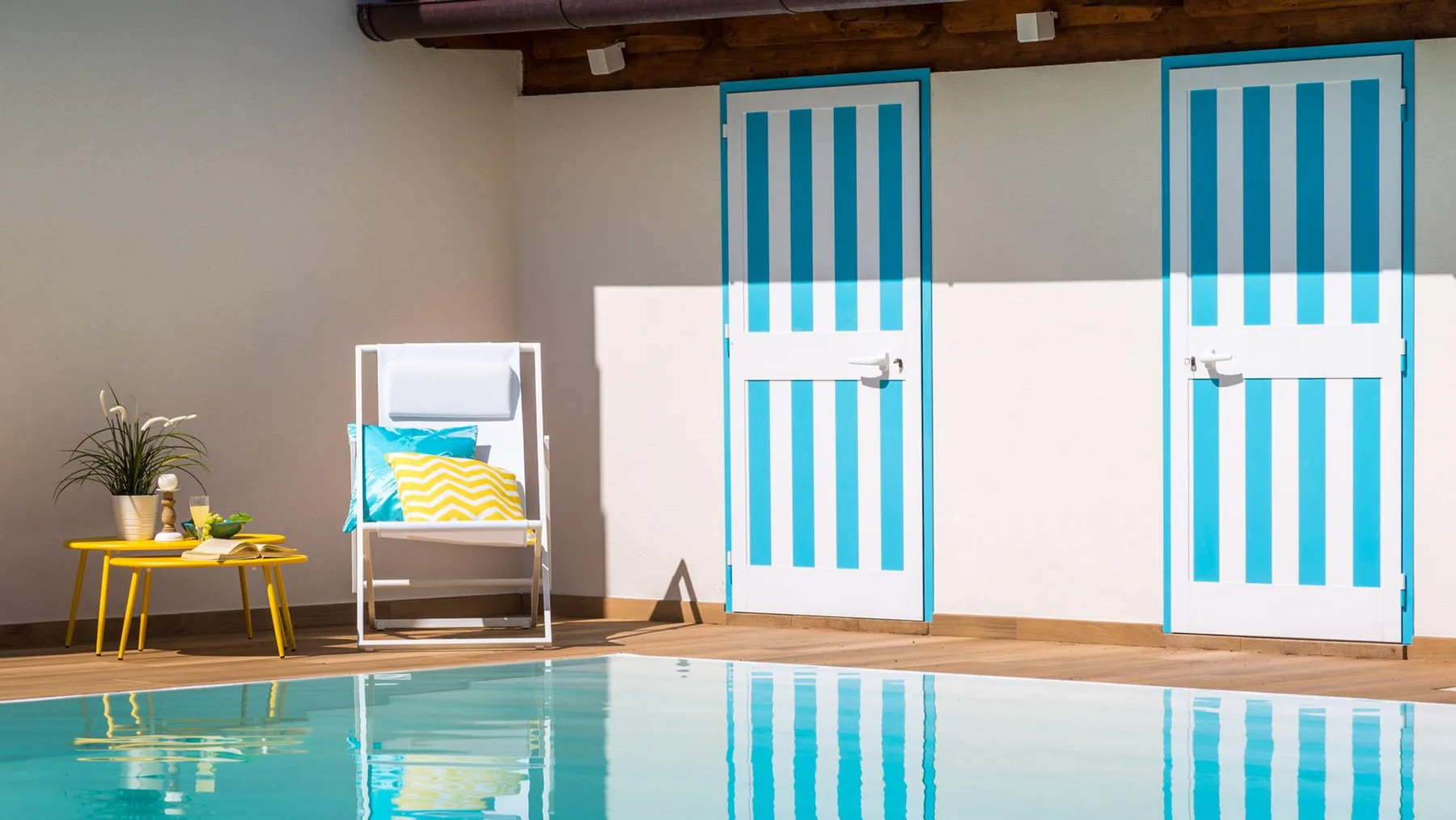 A swimming pool beside a patio with blue-and-white striped doors.