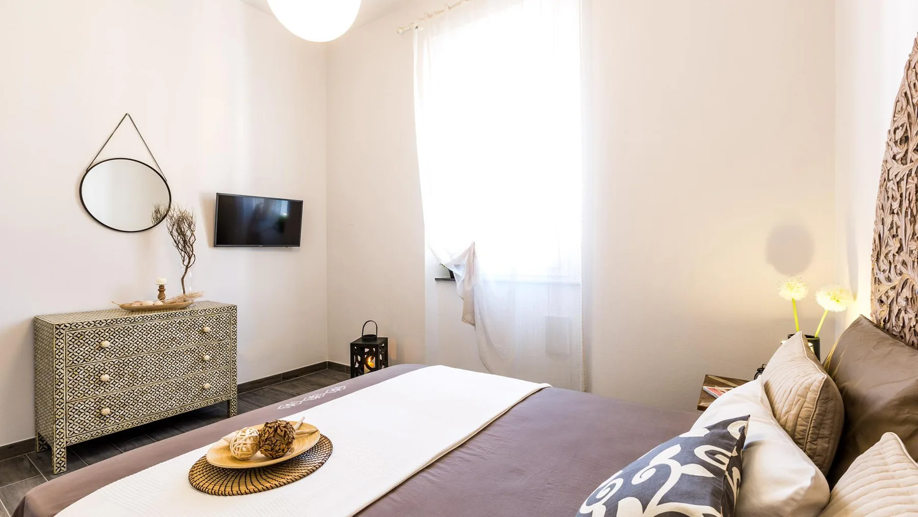 A bright bedroom with a bed, bedside lamps, and a dresser.
