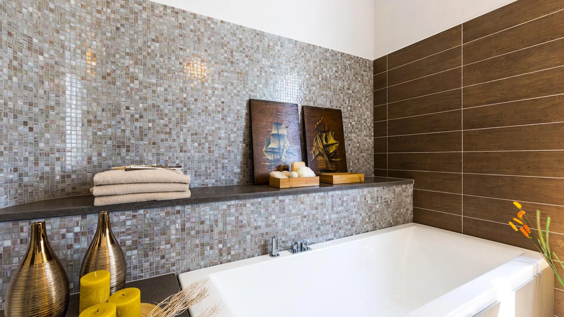 A bathroom with a bathtub, tiled walls, and folded towels.
