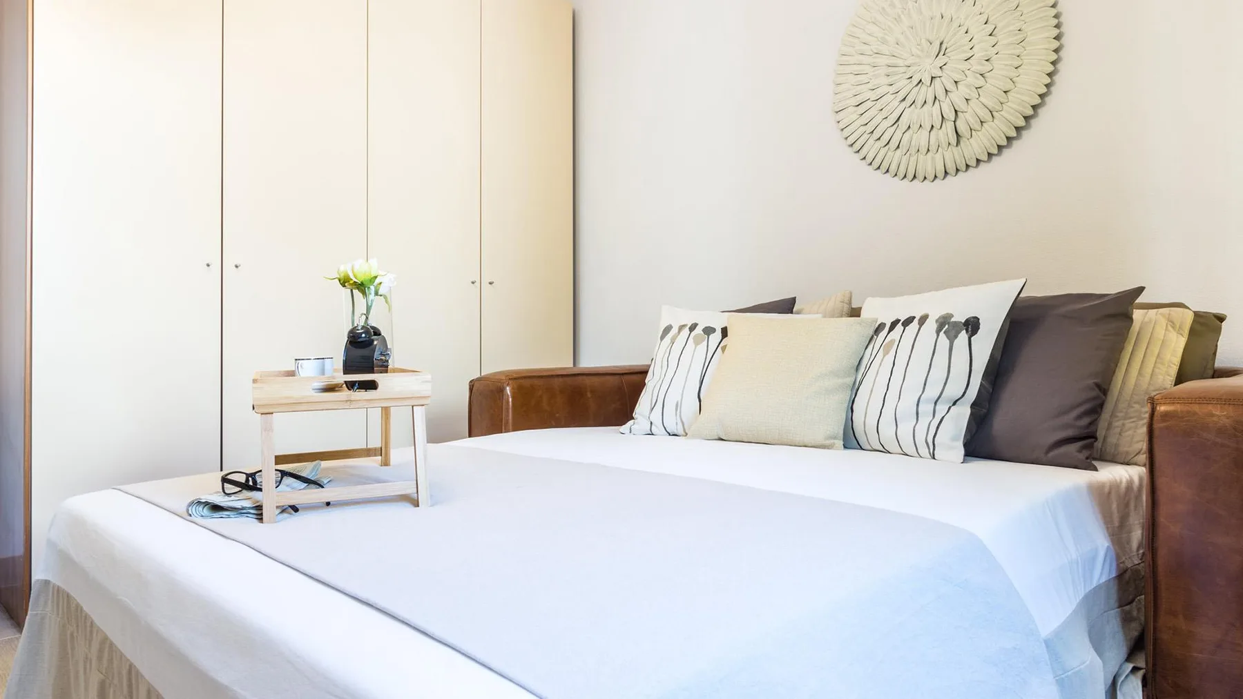 A bedroom with a neatly made bed and decorative pillows.