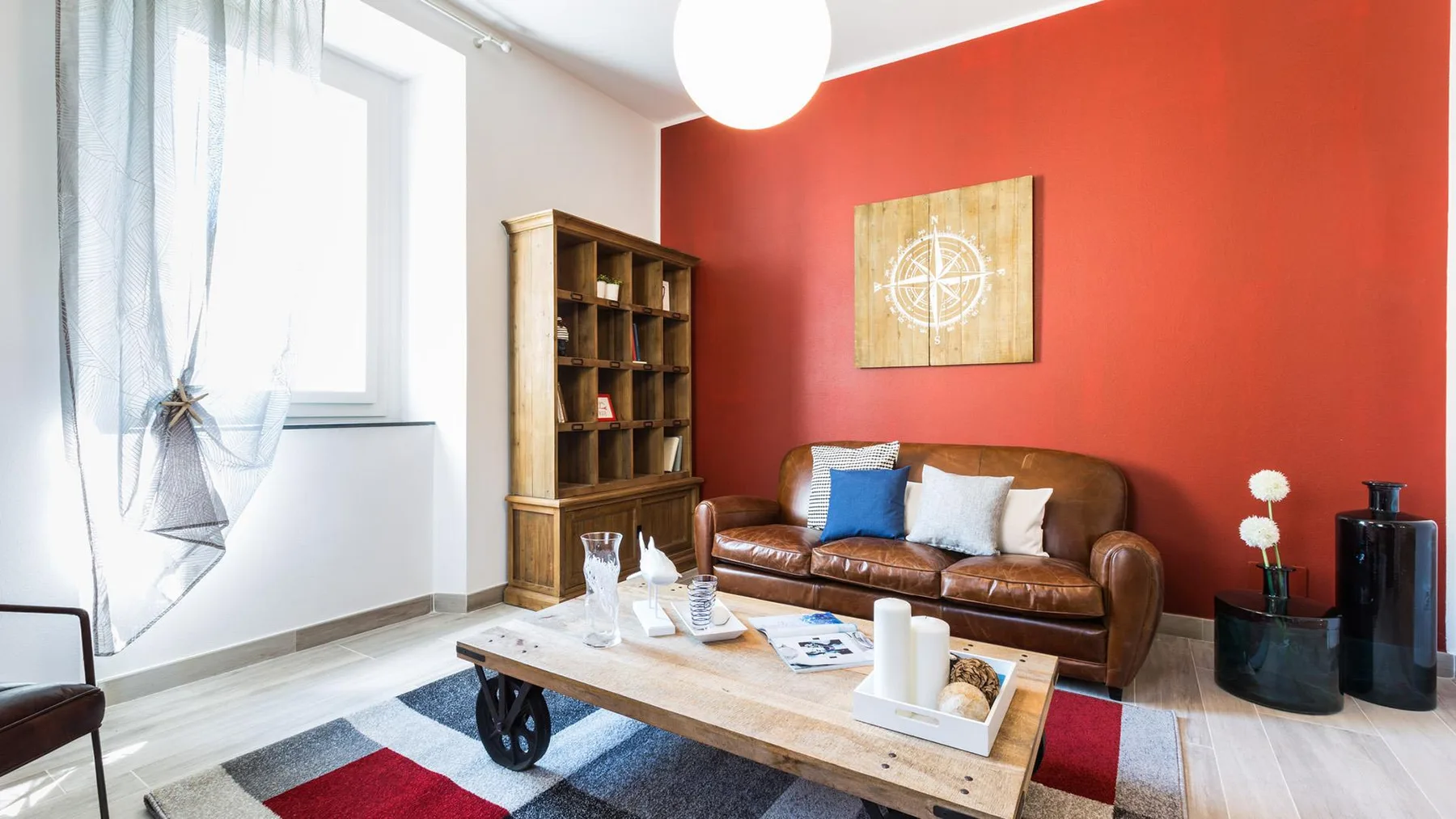 A living room with brown seating, a wooden coffee table, and a red accent wall.