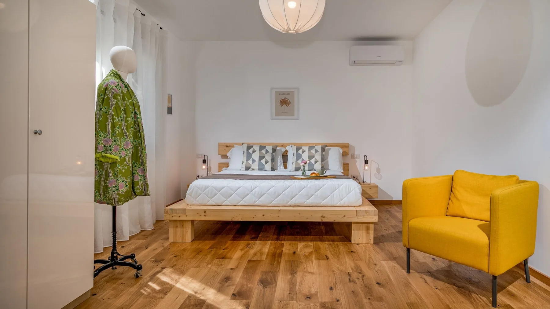 Un dormitorio con una cama elevada y un sillón amarillo intenso.