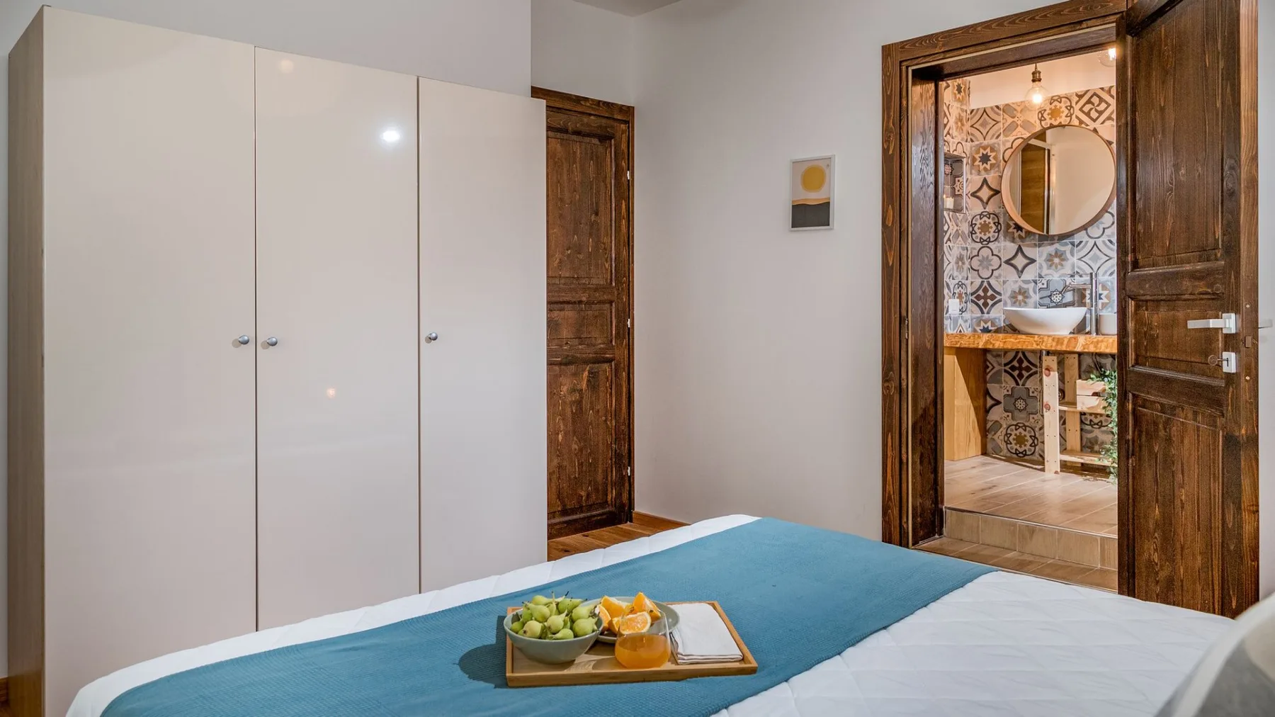 Un dormitorio con una cama y vista a un baño con azulejos estampados.