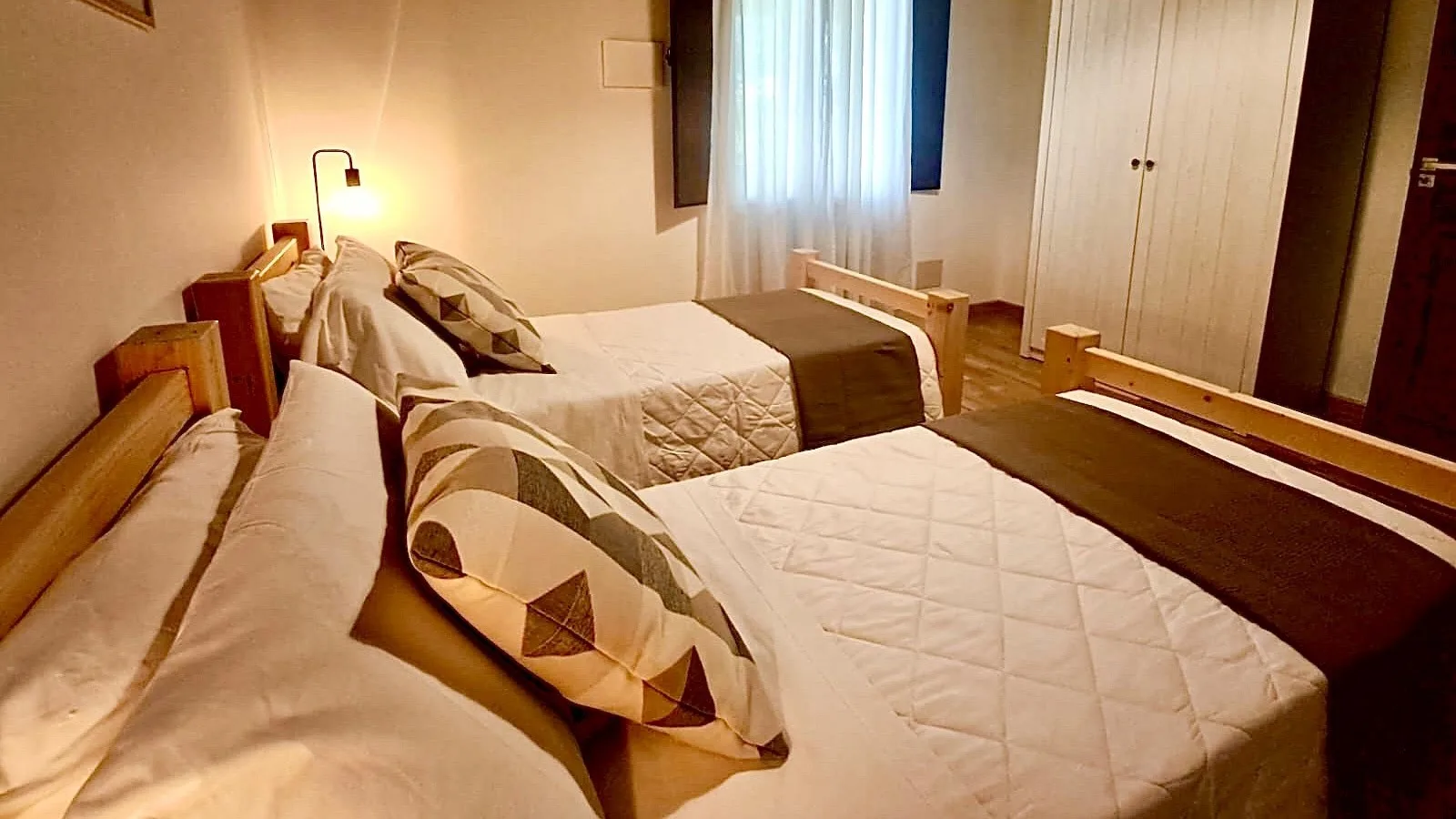 Un dormitorio con camas arregladas y una ventana con cortinas.