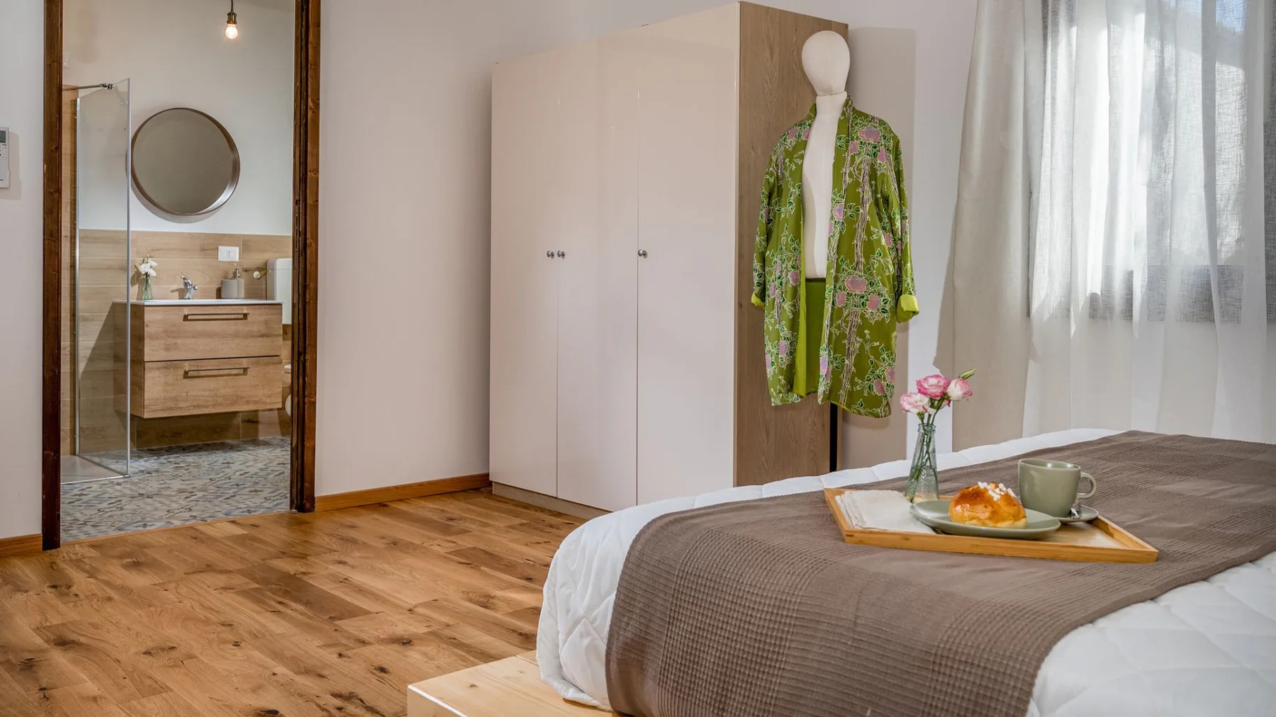 Un dormitorio con cama, armario y una prenda expuesta junto a la ventana.