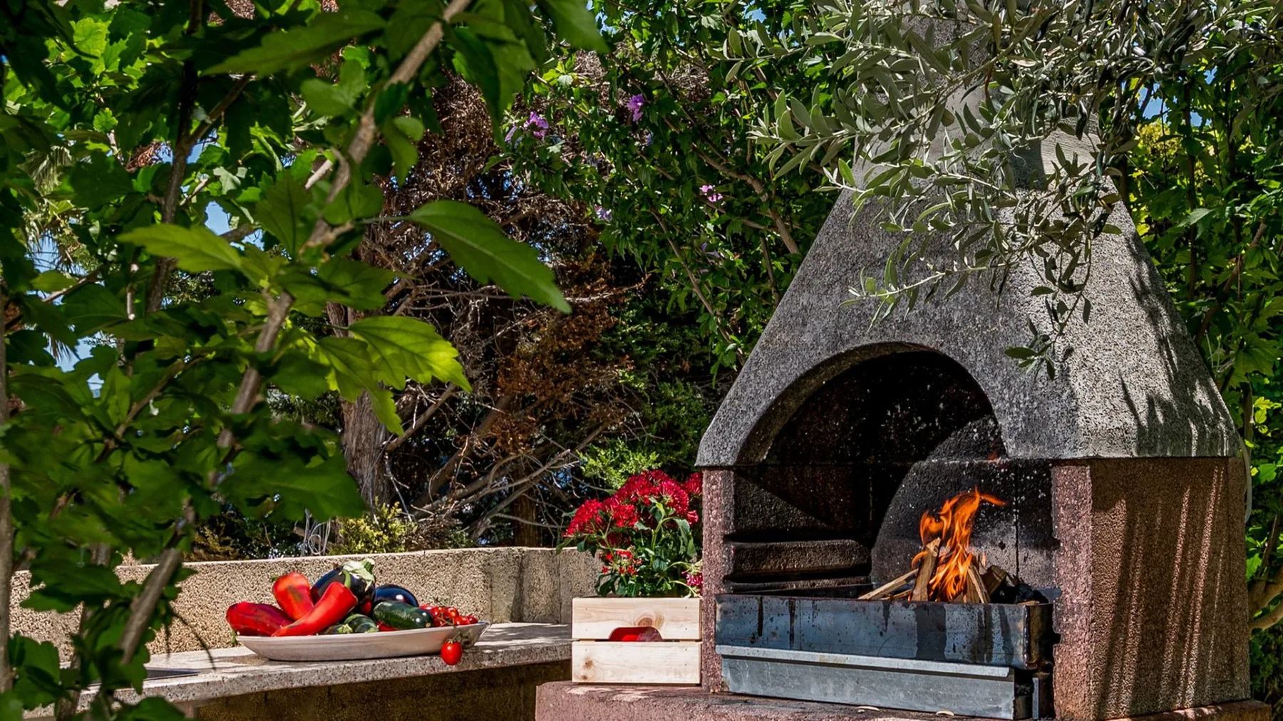 Una chimenea exterior encendida está junto a una encimera de jardín.