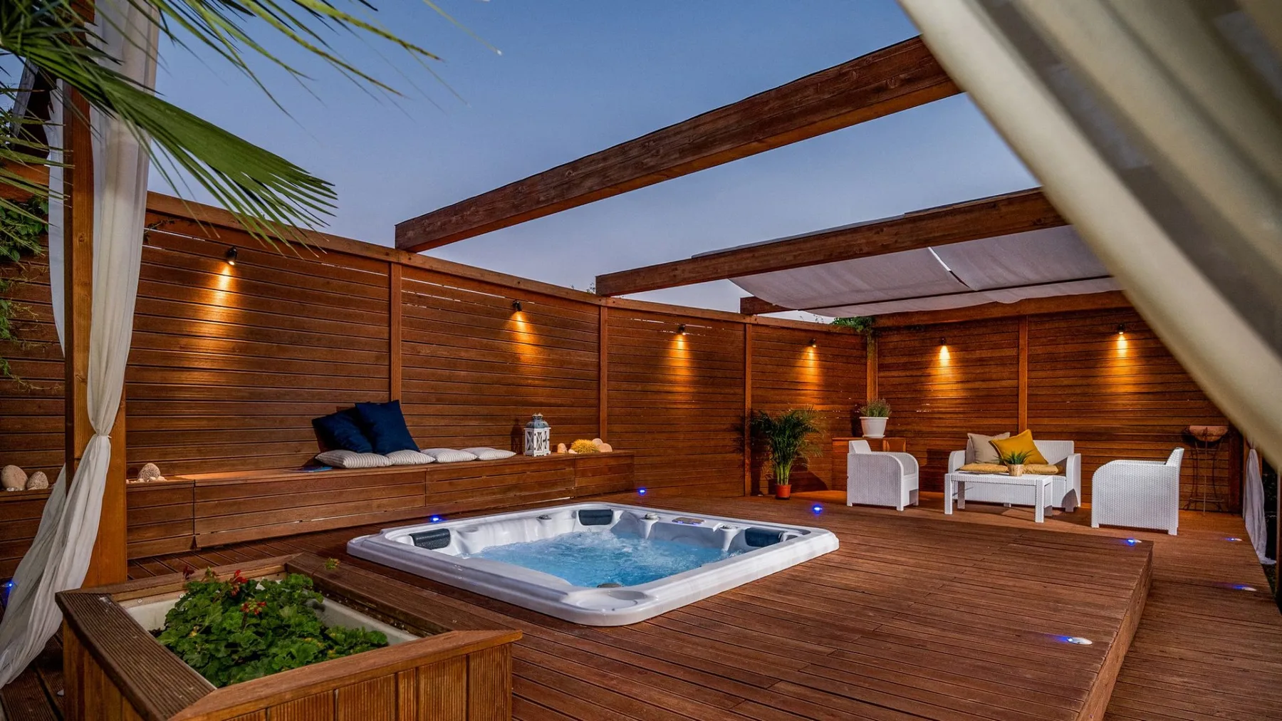 Una bañera de hidromasaje al aire libre se encuentra en una terraza de madera rodeada de paneles de madera.