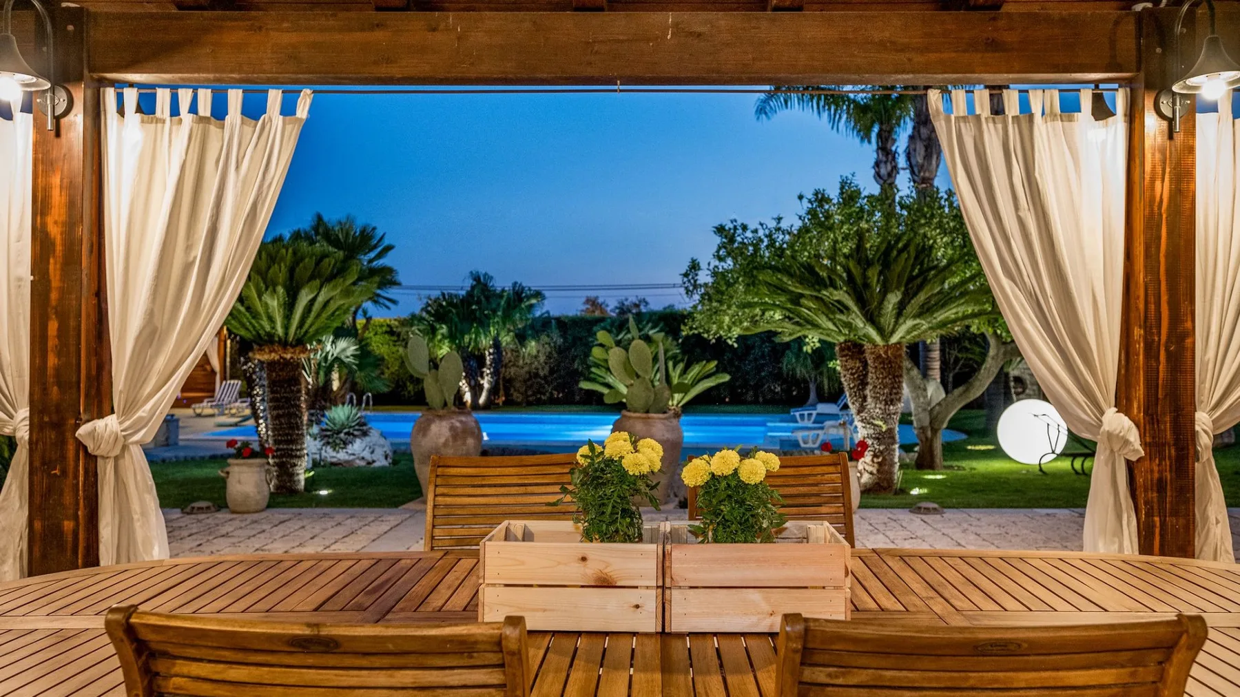 Una zona exterior de asientos de madera da a una piscina y un jardín.