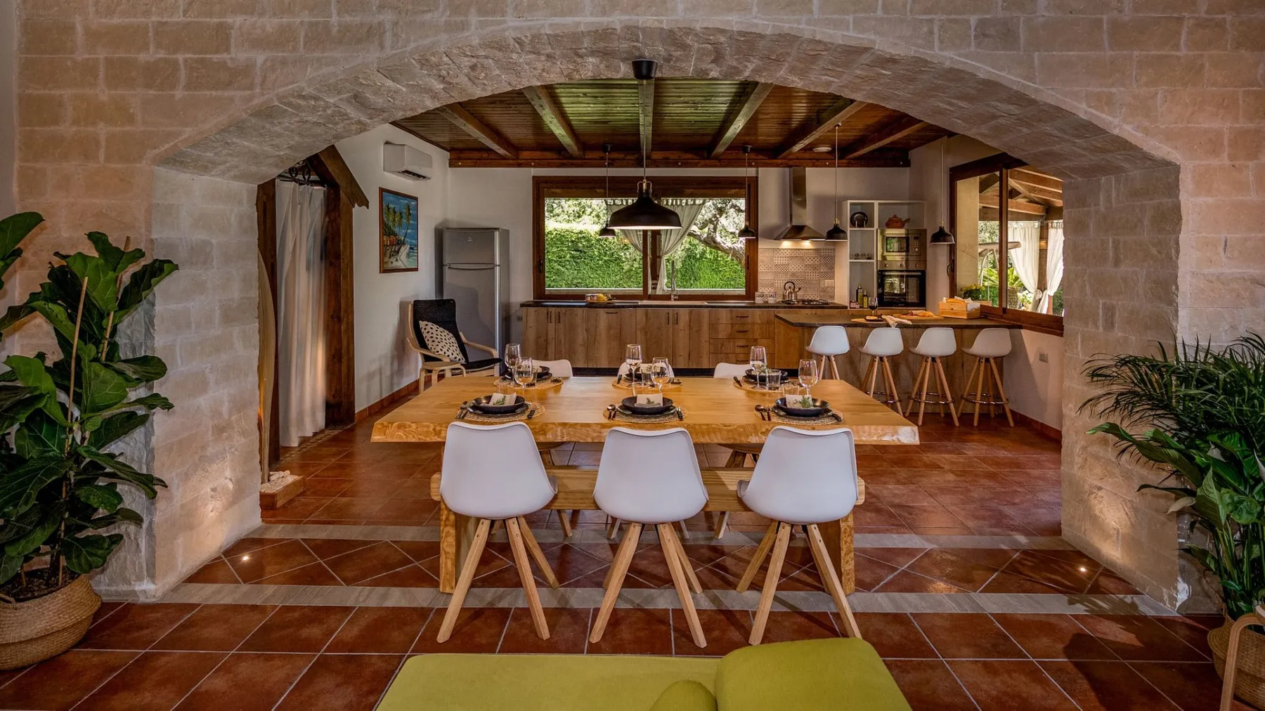 Un comedor se abre a una cocina bajo un amplio arco de piedra.