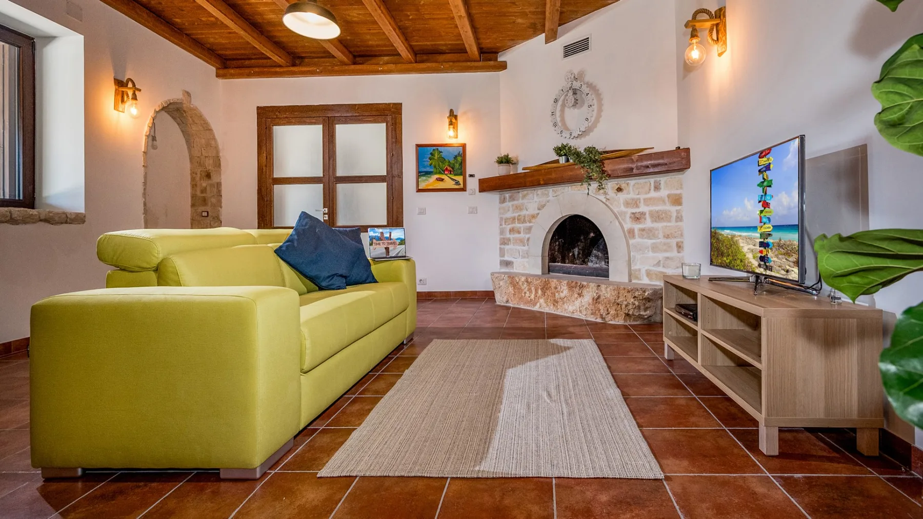 Una sala de estar con asientos verdes, una chimenea y un televisor.