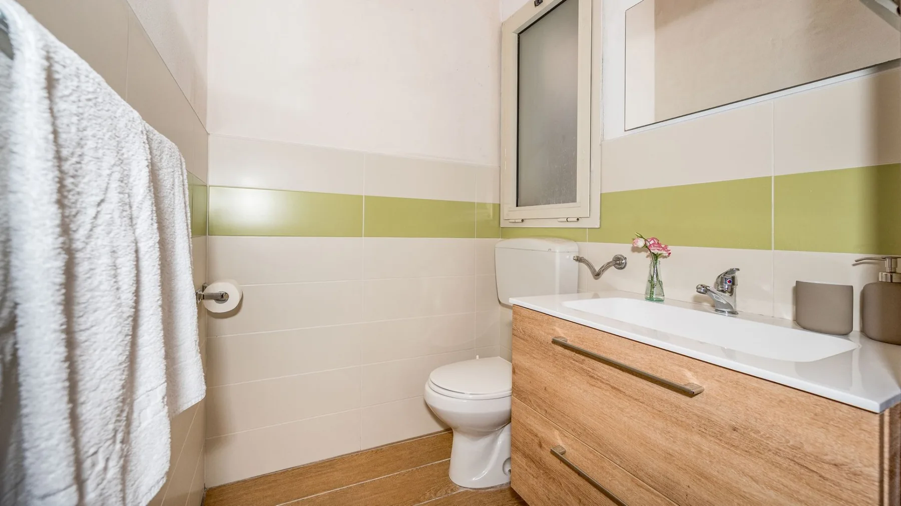 Un baño con inodoro, mueble de lavabo y toallas junto a la ducha.