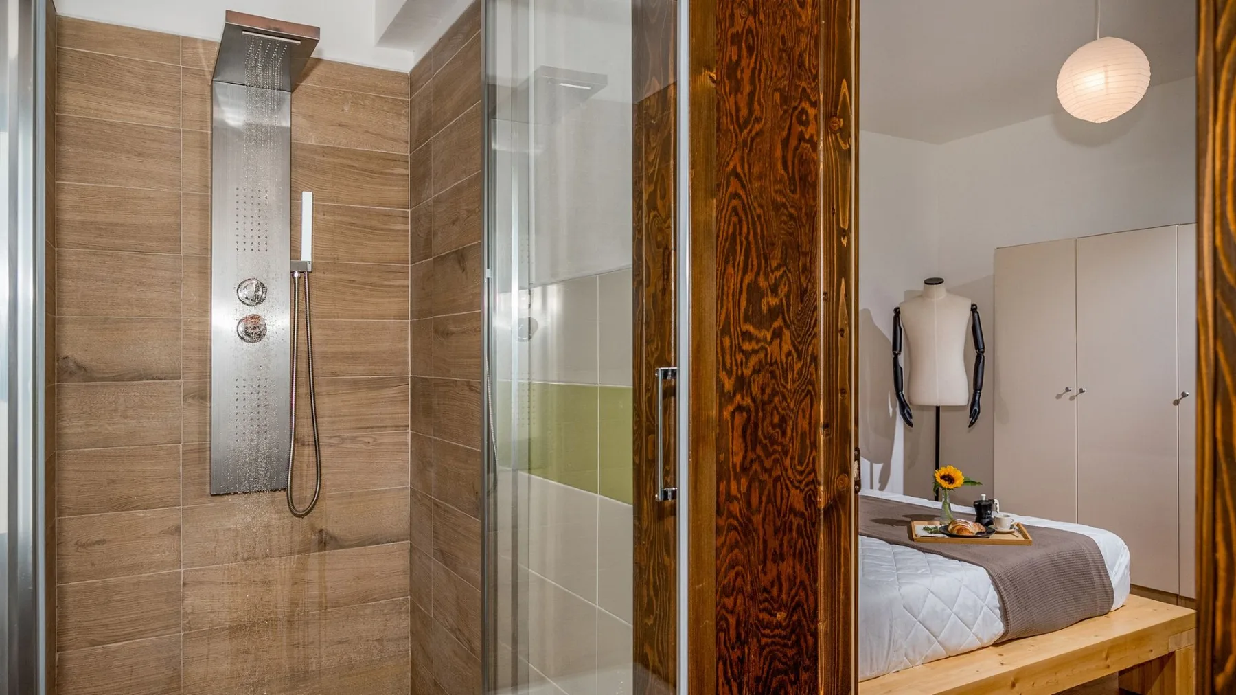 Un dormitorio con cama y armario, junto a una ducha de vidrio.