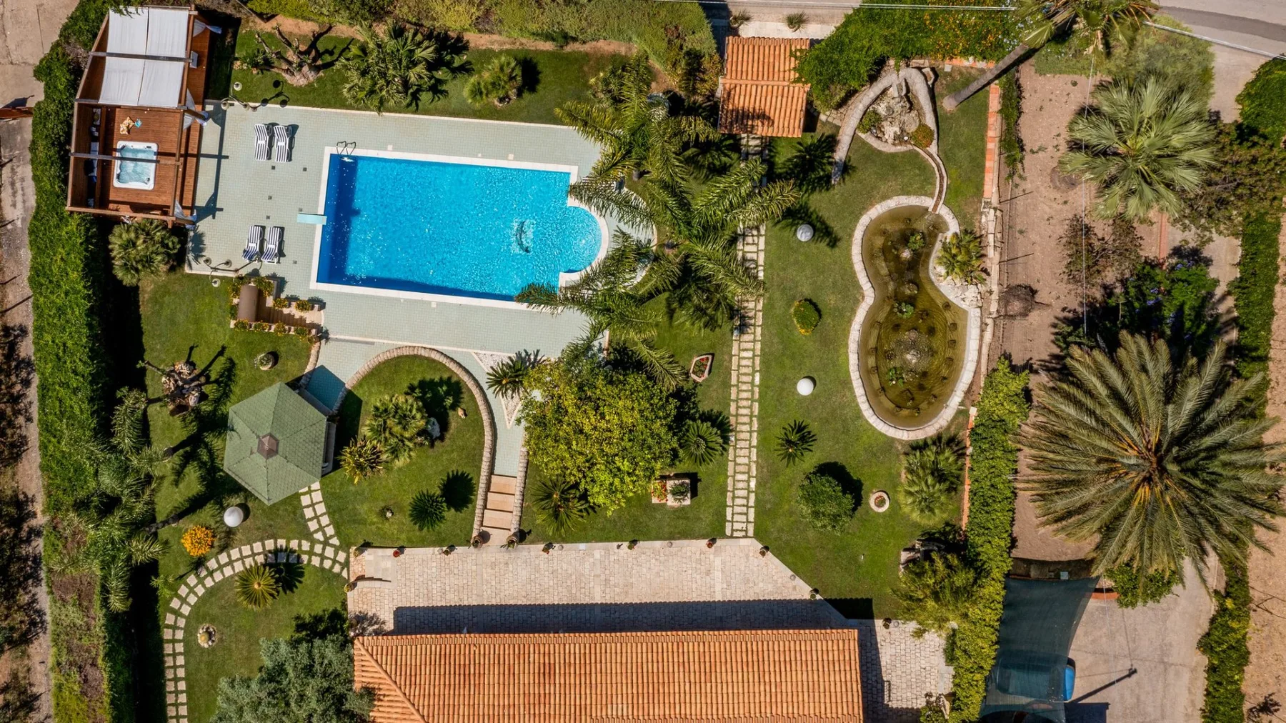 Vista aérea de jardines con una piscina y senderos.