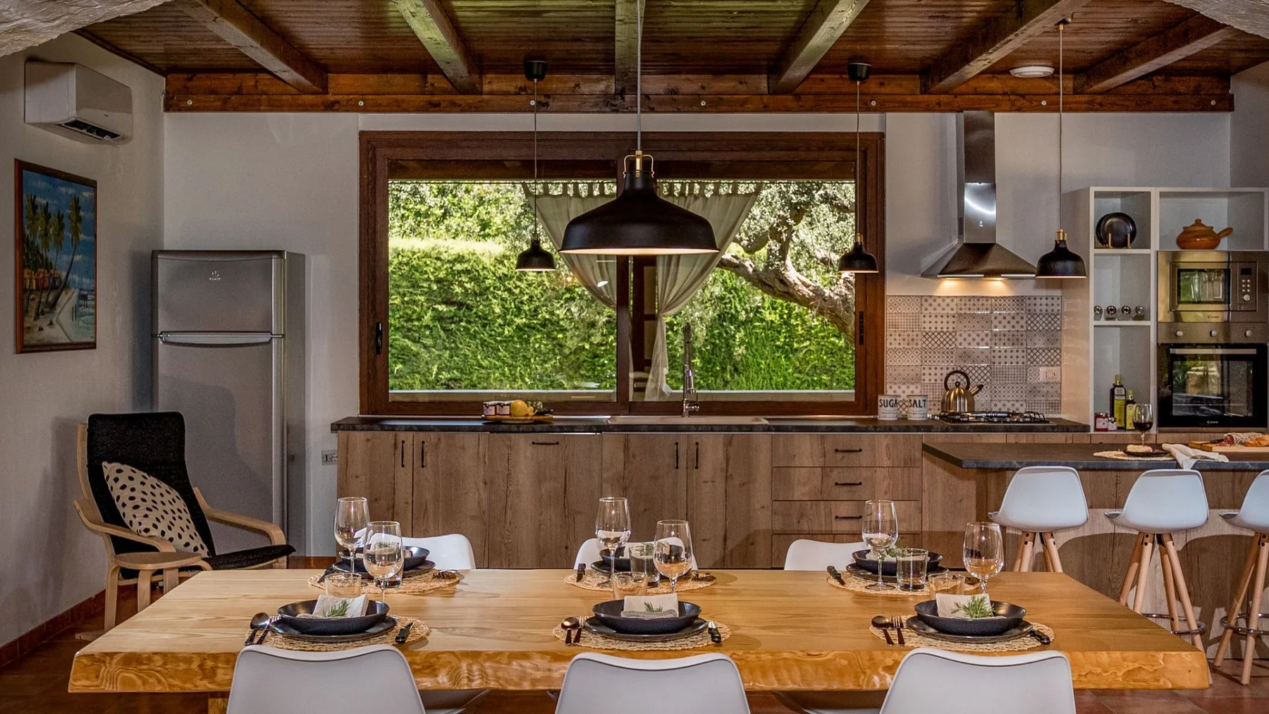 Comedor y cocina abierta, con una mesa de madera preparada para comer.