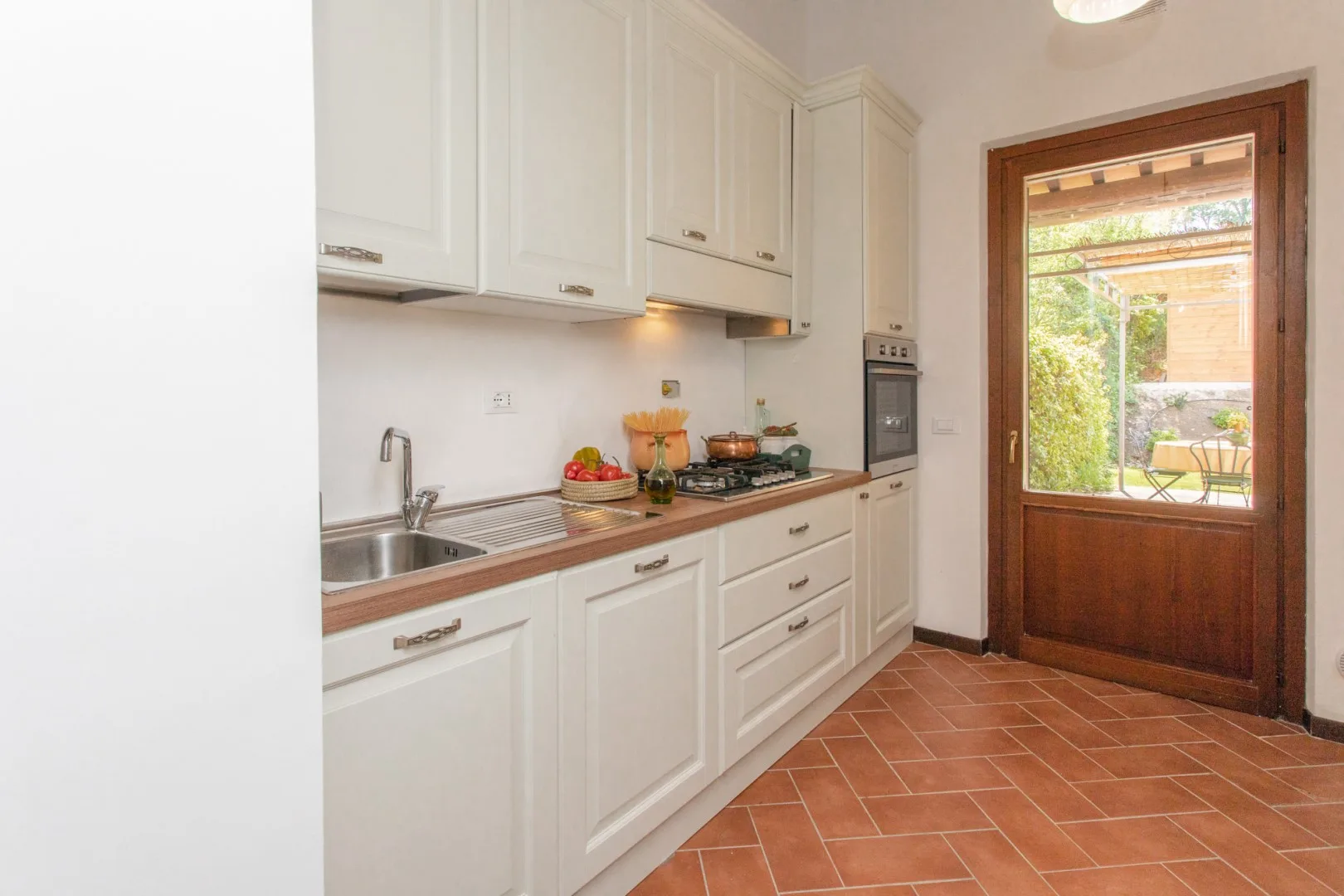 A bright kitchen with white cabinets, a countertop, and a glass-paneled door.