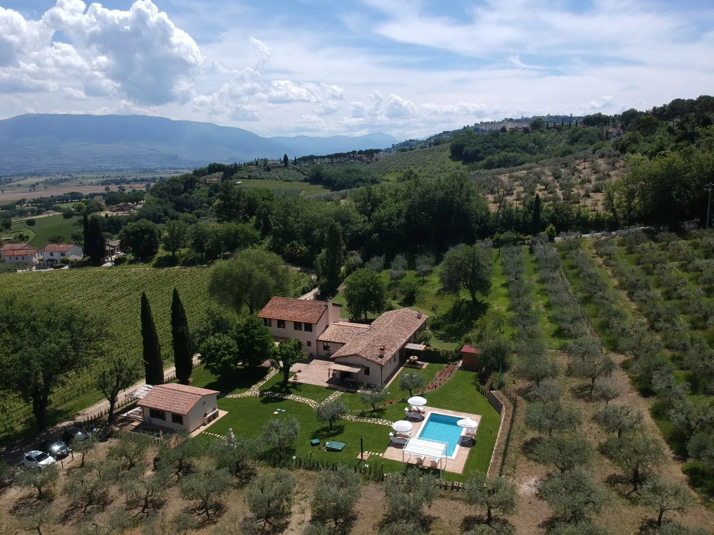 An aerial view of a countryside property with a swimming pool and surrounding hills.