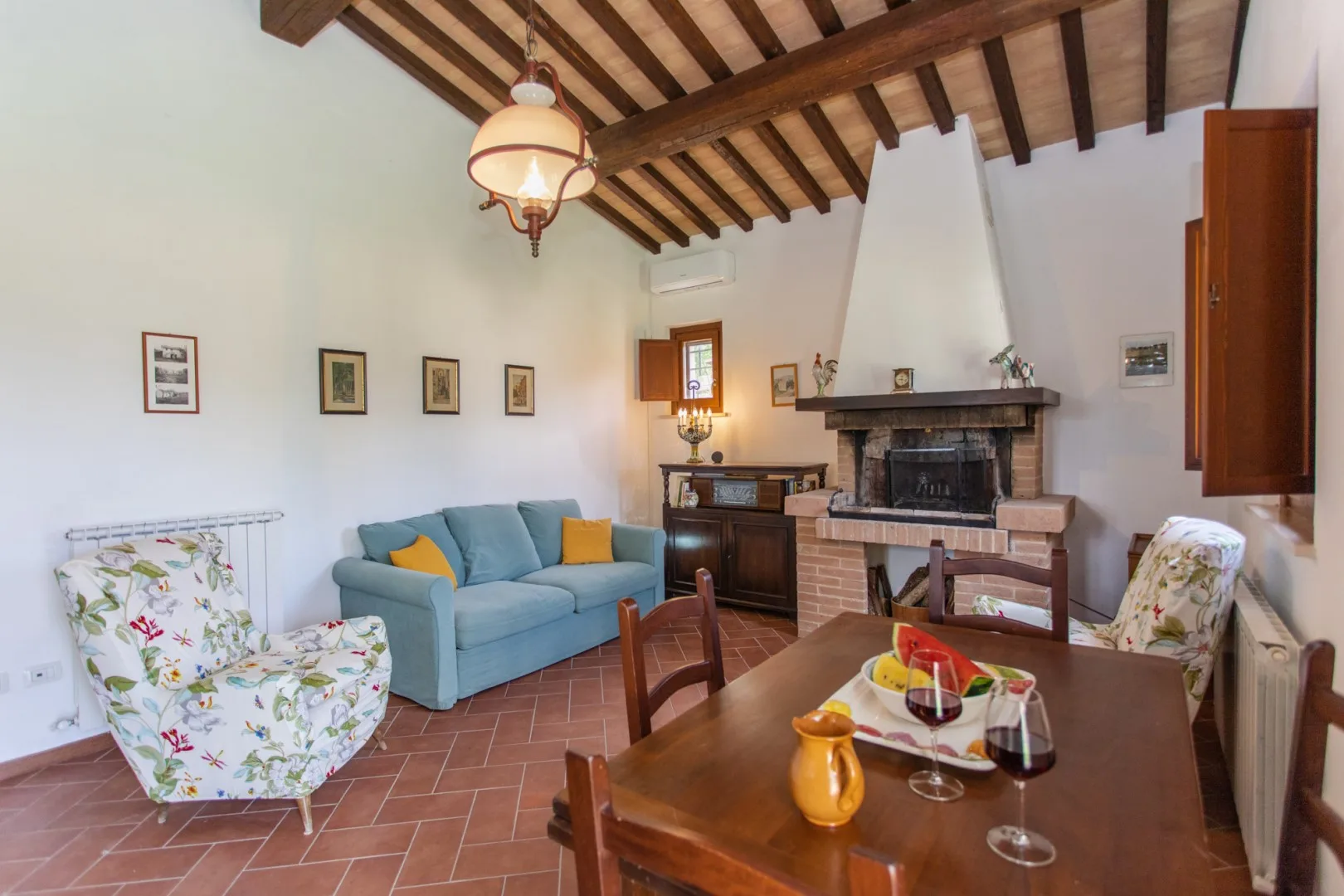 A dining and sitting room with a wooden table, blue seating, and a fireplace.