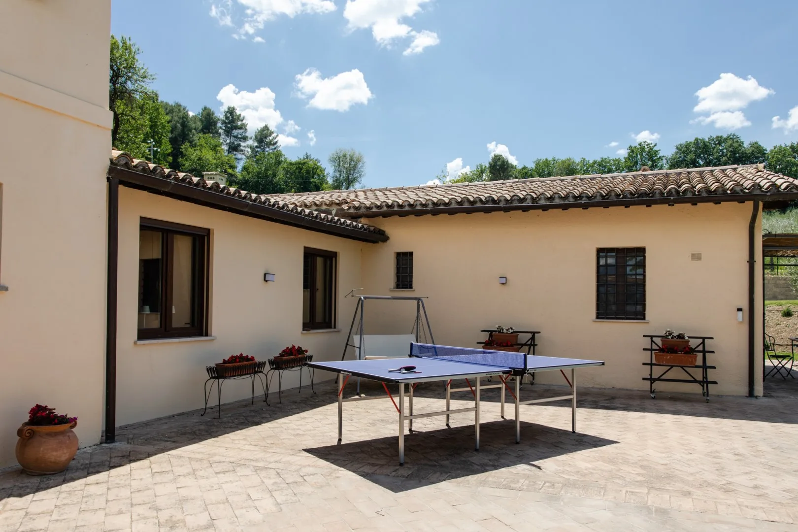 A paved courtyard with a table tennis table in front of a low building.