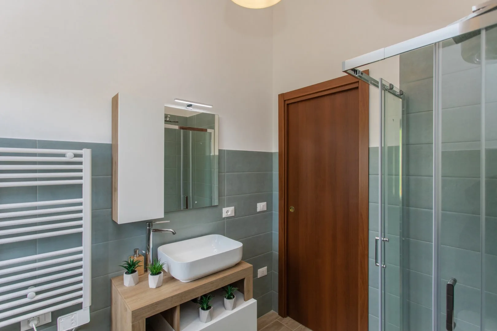 A bathroom with a sink, mirror, and glass shower enclosure.