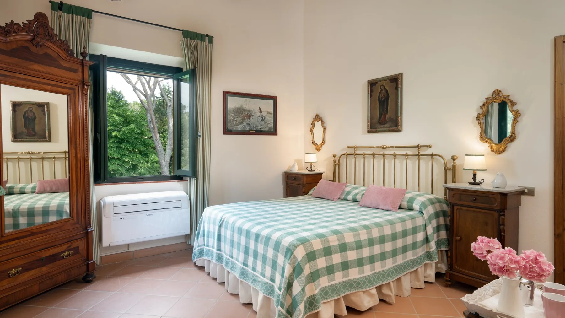 Un dormitorio con una cama vestida de cuadros verdes y blancos y una ventana con vista a los árboles.