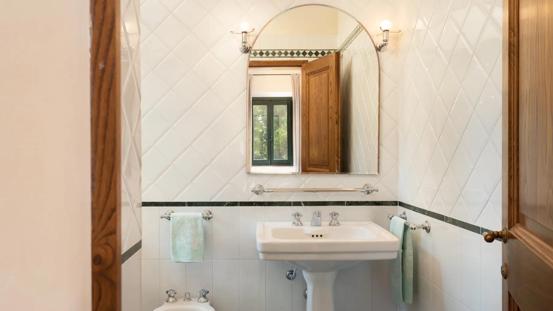Un baño alicatado con lavabo y un gran espejo de pared.