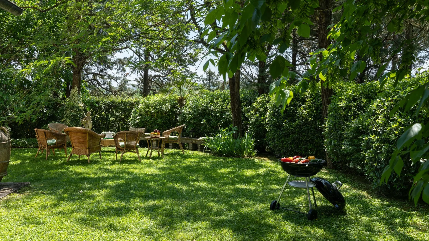 Una zona de estar en el jardín con una parrilla sobre el césped.
