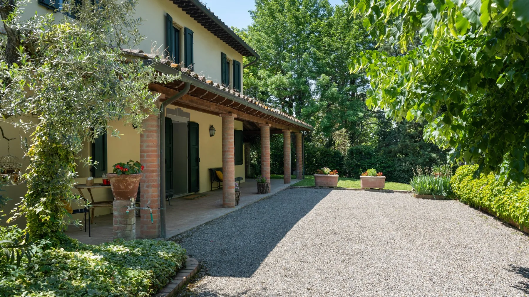 Una casa de dos plantas con porche cubierto da a un patio de grava.