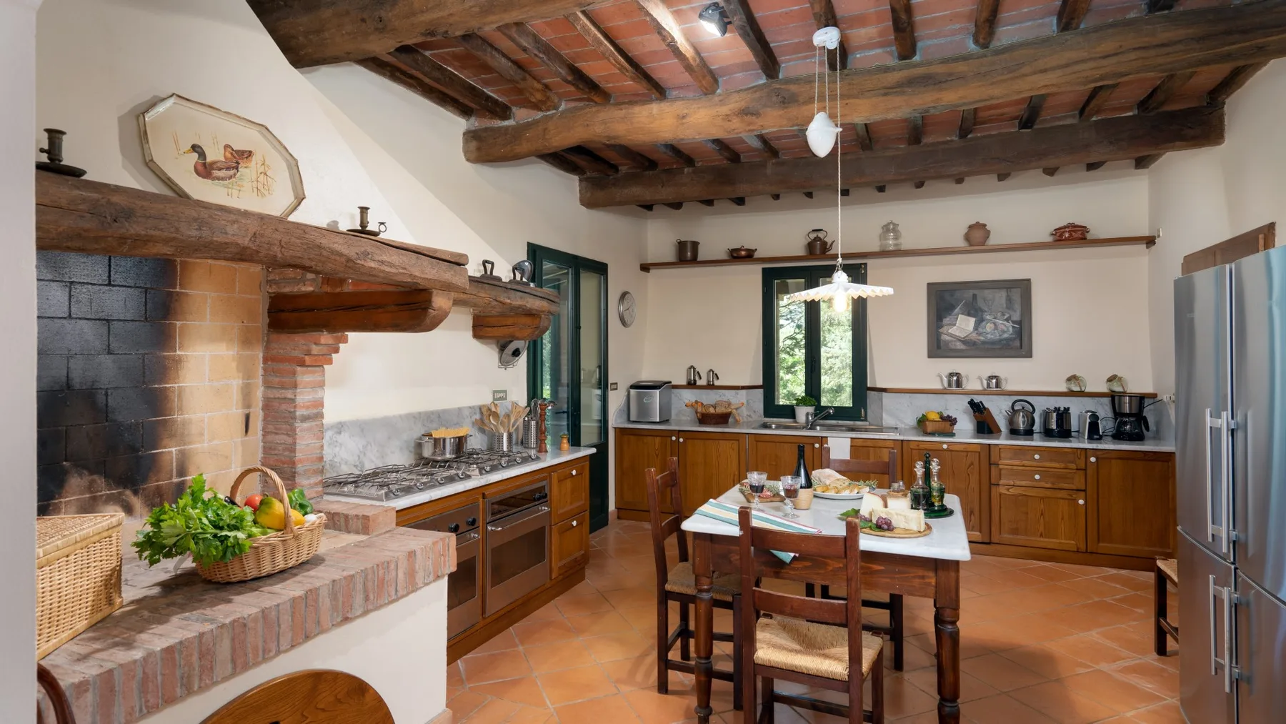Una cocina rústica con gabinetes de madera, una mesa central y vigas expuestas en el techo.