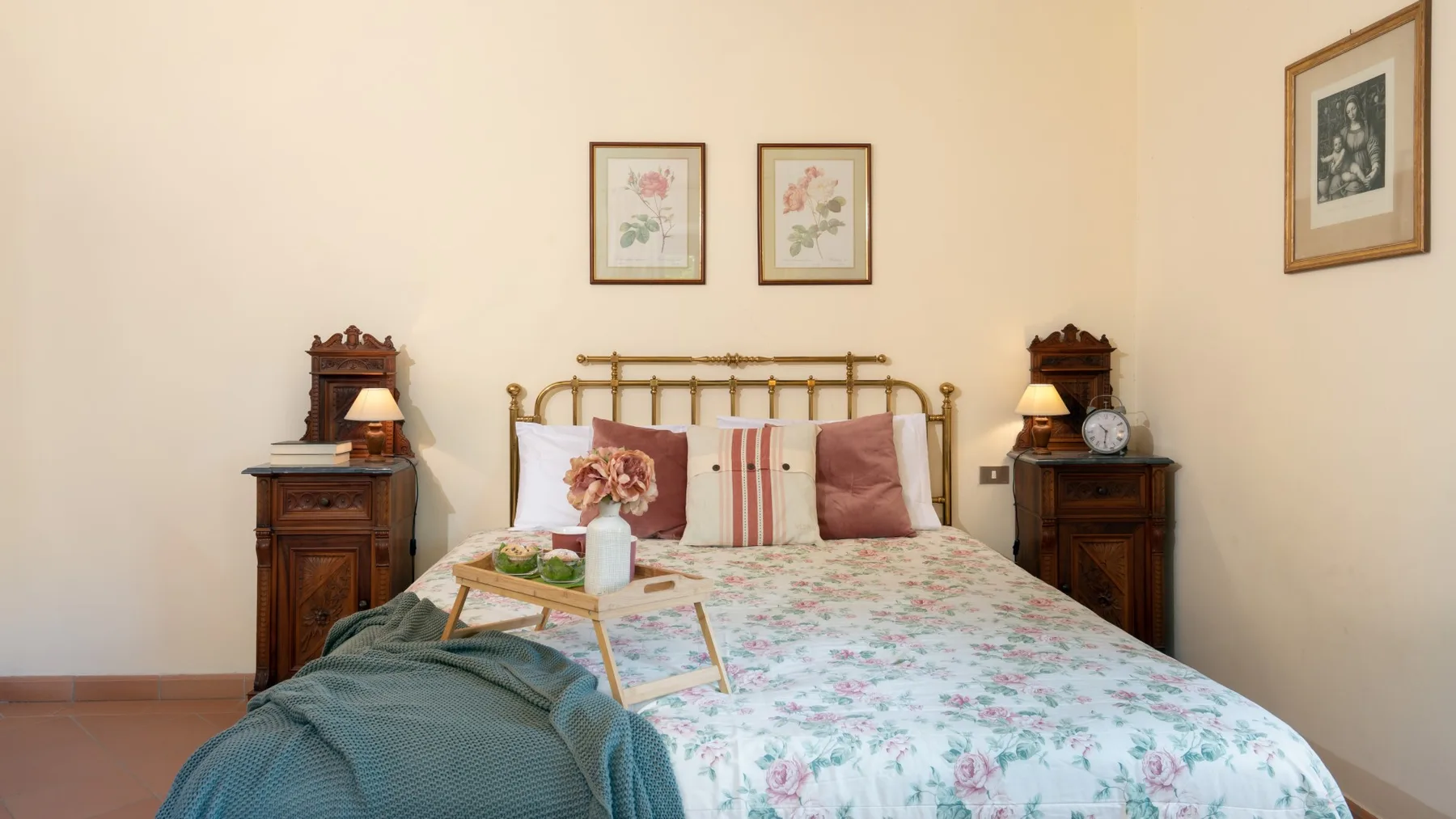 Un dormitorio con una colcha floral, cabecero de madera y mesillas a juego.