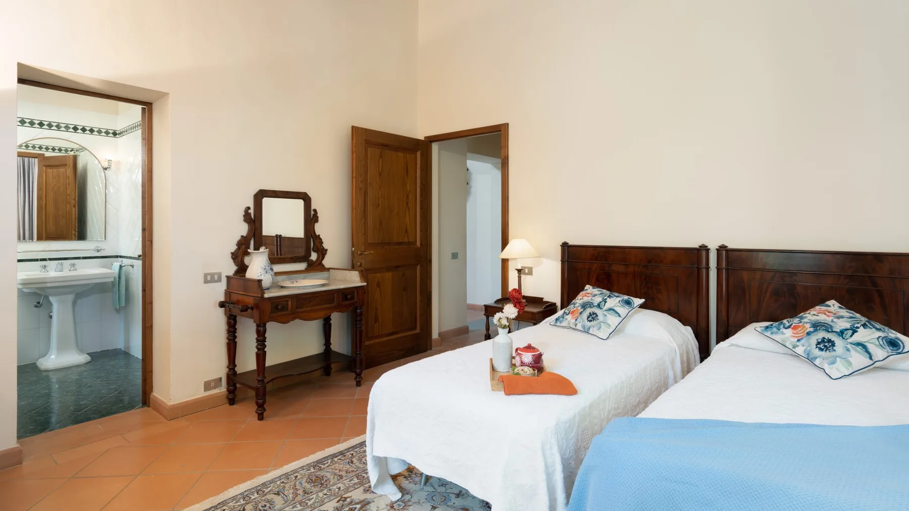 Un dormitorio con dos camas, un tocador de madera y una puerta abierta.